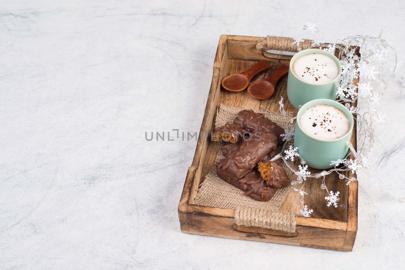 Coffee cups and chocolate coated gingerbread in a wooden basket, empty copy space, christmas season