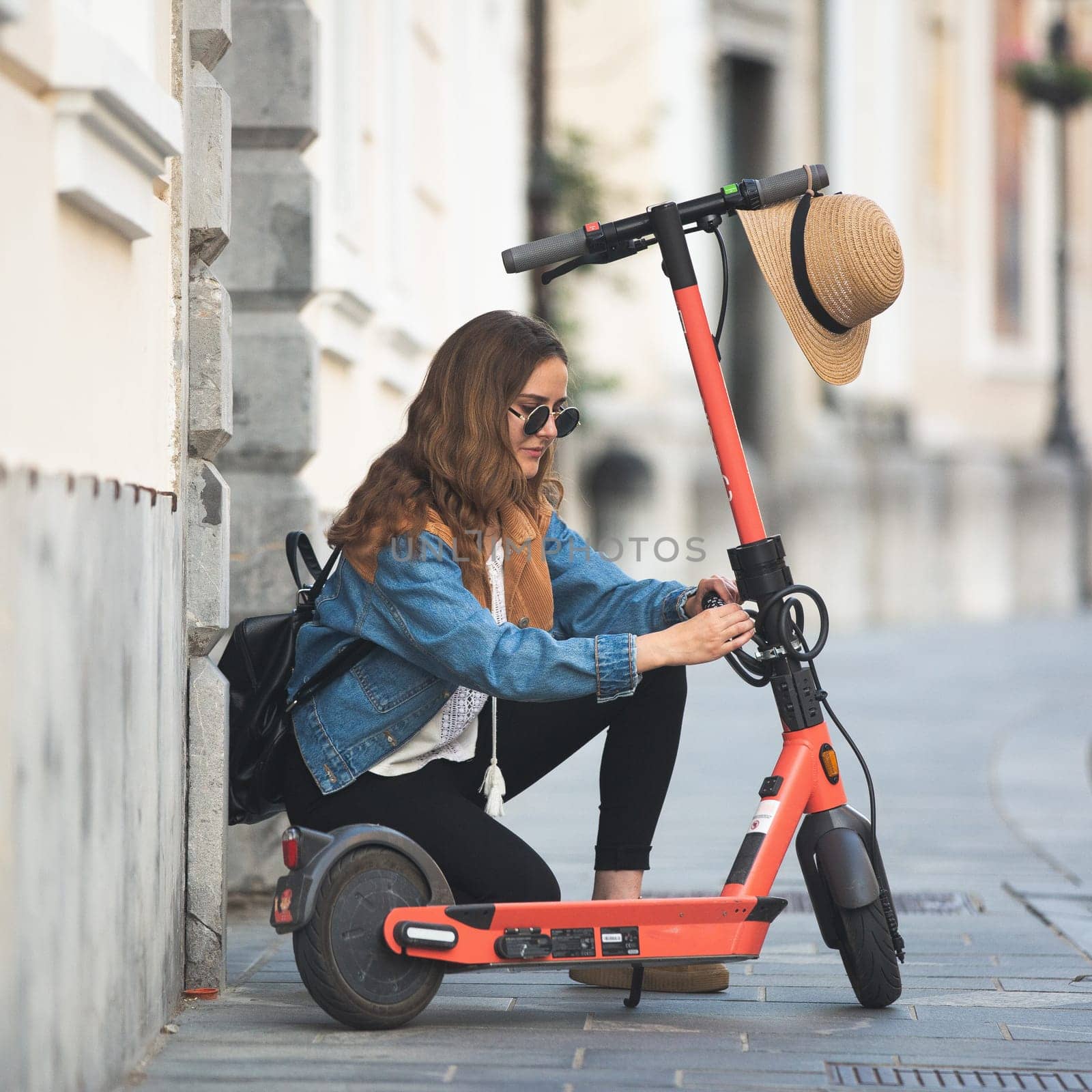 Electro-mobility. Traveler unlocking an e-scooter on the street. Traveler exploring old town on environmentally friendly electric scooter.