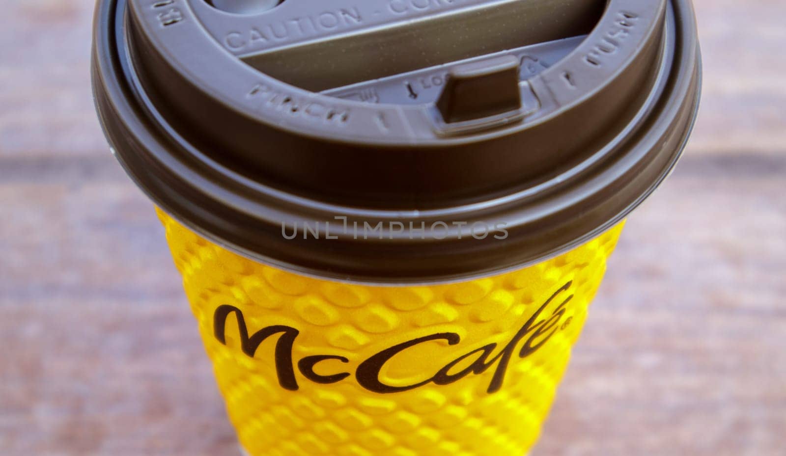 Paper yellow glass glass with coffee for McCafe drinks on the table against blurred city from McDonald's. Fast food business background. Fast food restaurant menu. Ukraine, Kiev - September 13, 2021