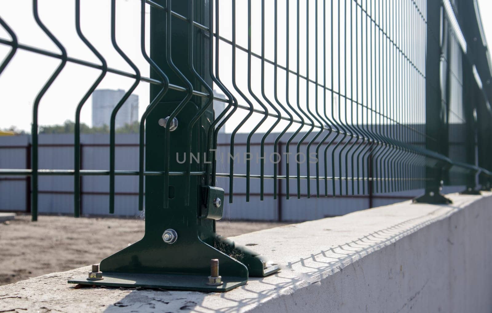 Steel lattice green fence with wire. Fencing. Grid industrial wire fence panels, pvc metal. Installation of sectional fencing. Welded mesh fence. Installation of a grid for fencing the territory
