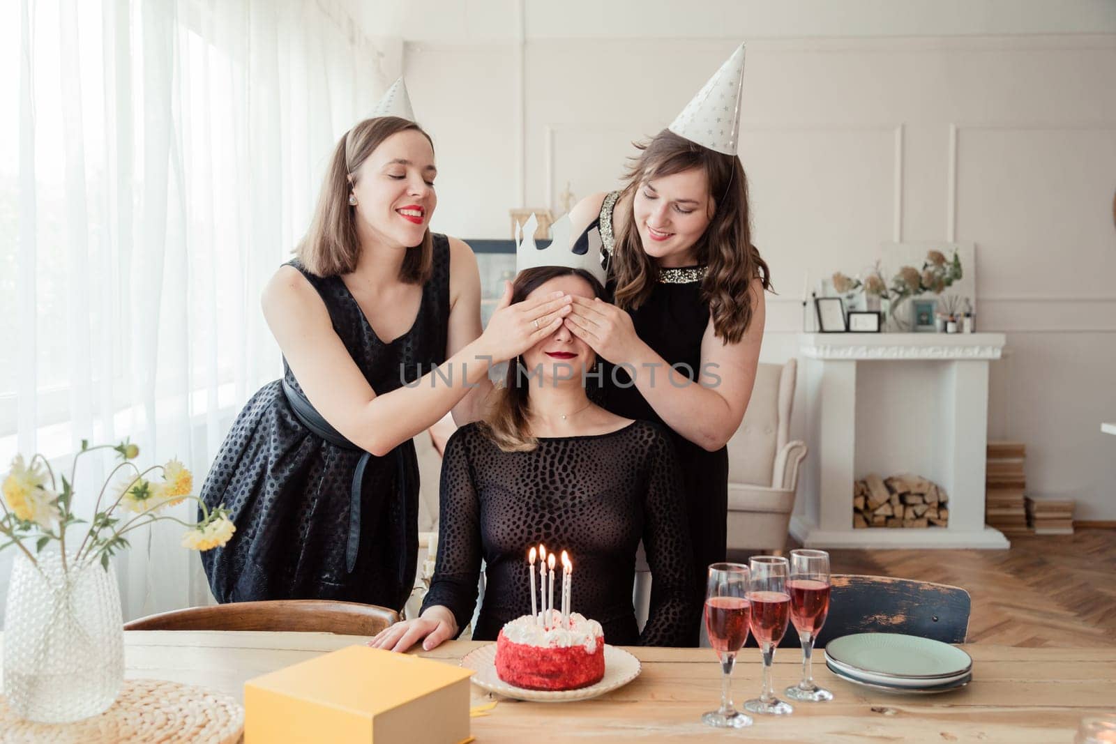 Two girls prepared a packed gift box for their birthday friend, closing eyes with hands, celebrating women's day, having glasses with champagne