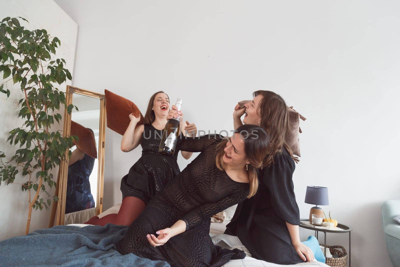 happy laughing girls having a pillow fight on the bed at home