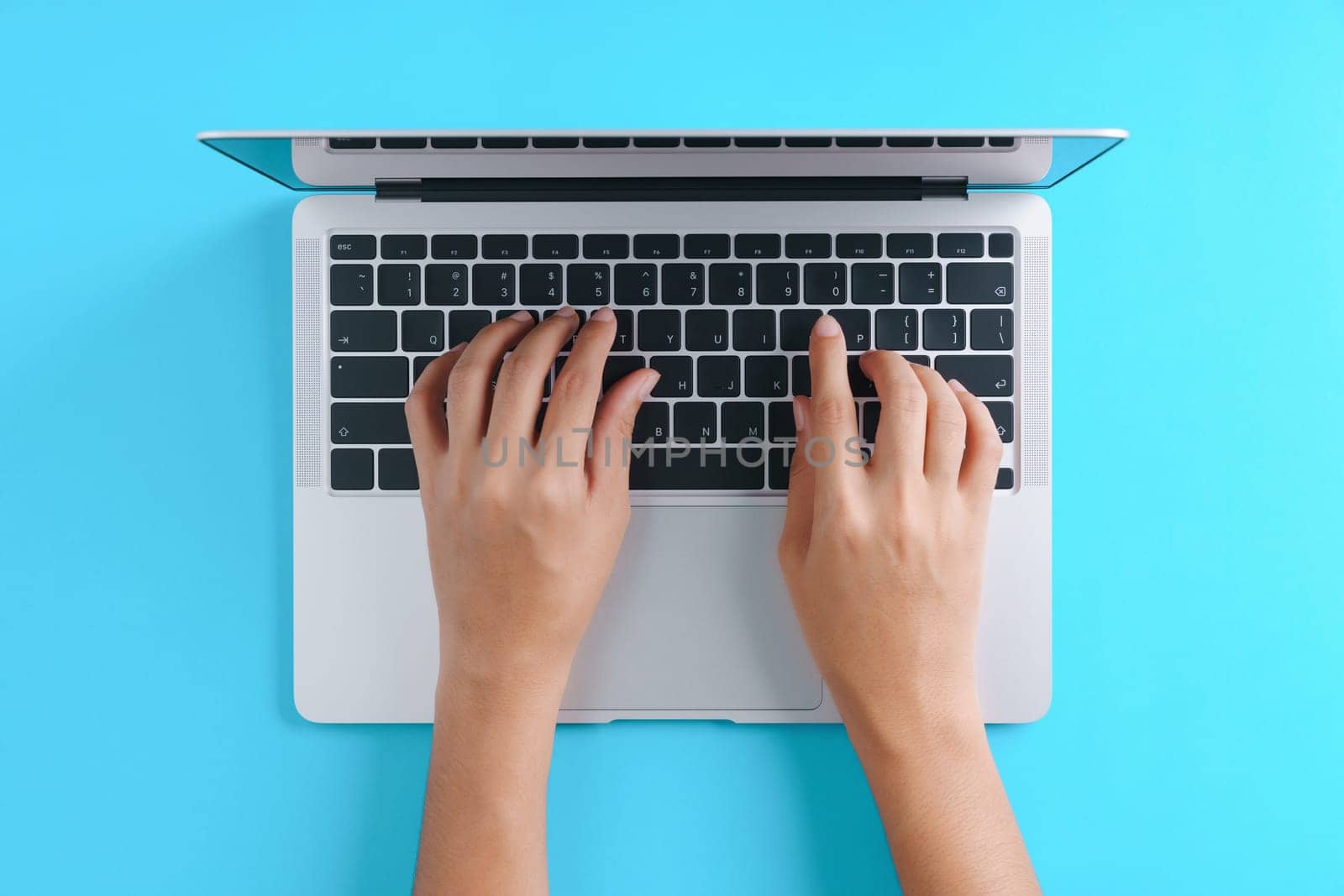 hand using laptop computer on blue background top view