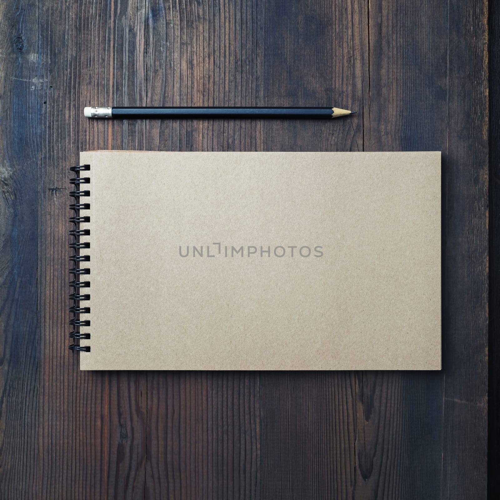 Blank kraft sketchbook and pencil on wood table background. Template for branding design. Flat lay.