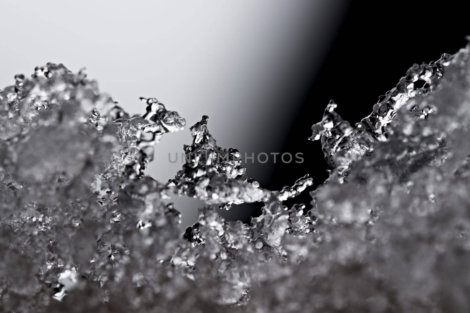 Thawing snow or frost, super macro close up image with an abstract background. Selective focus and soft black and white background. Microscopic detail