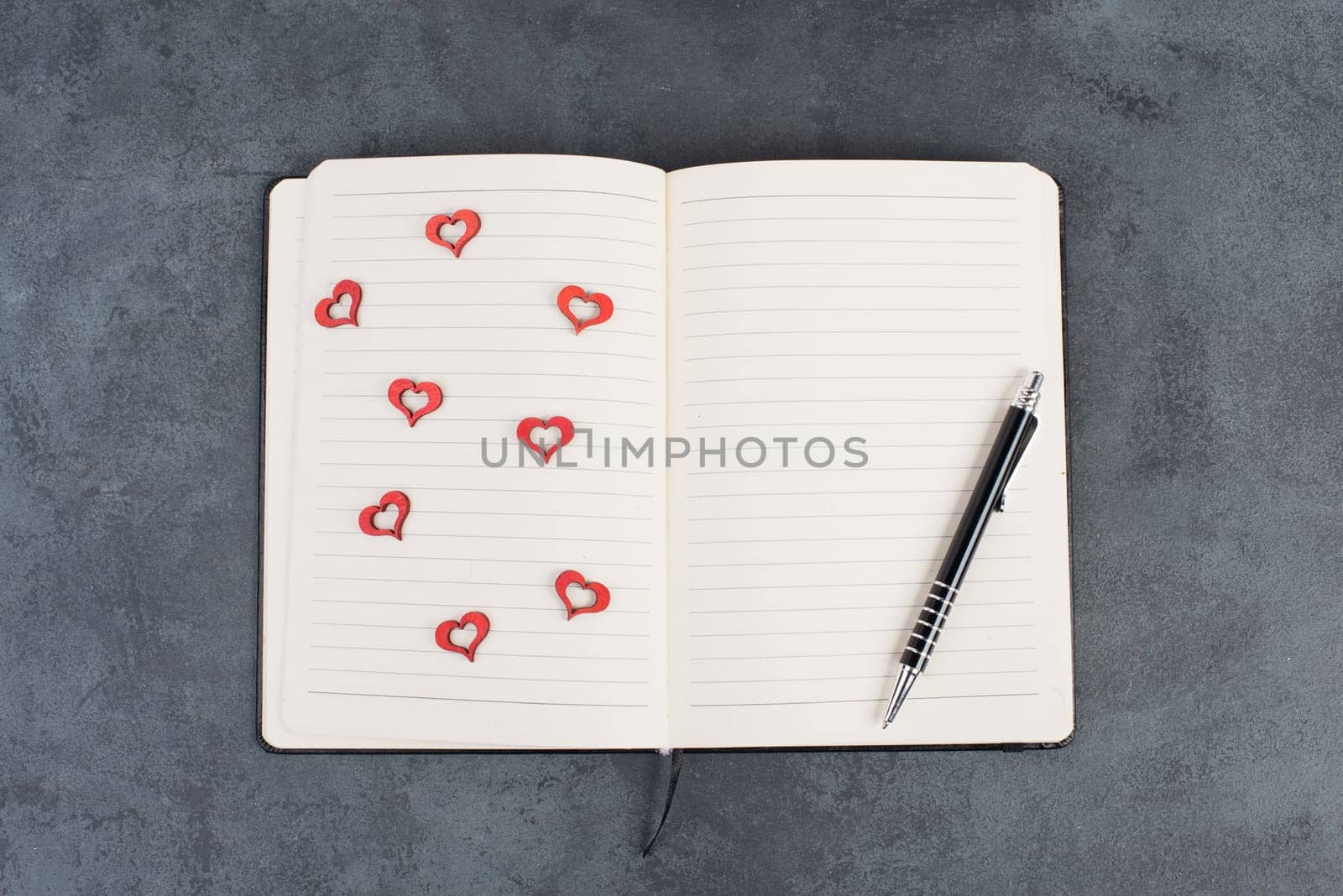 Empty notebook with wooden hearts and a pen