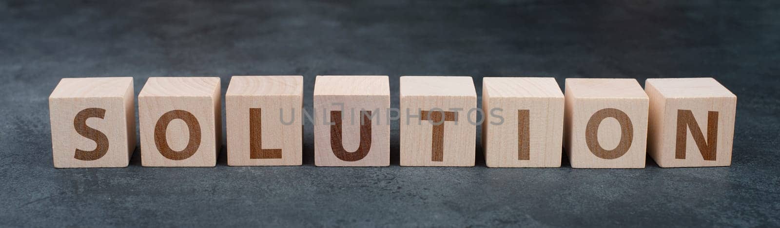 The word solution is standing on wooden blocks, dark background