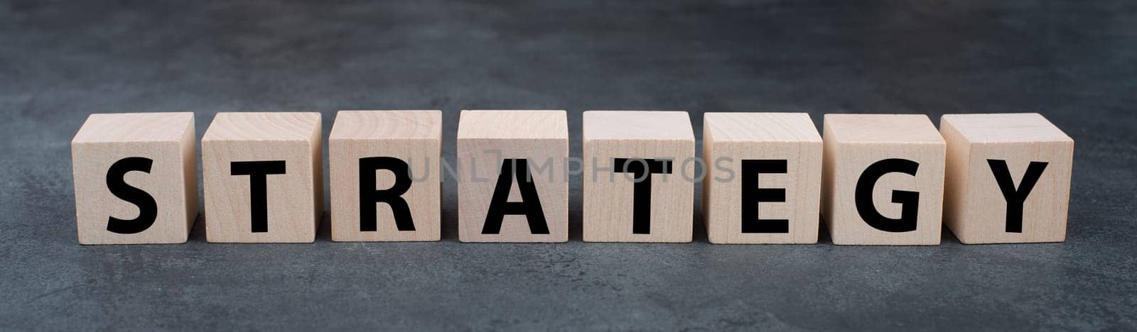 The word strategy is standing on wooden blocks, dark background