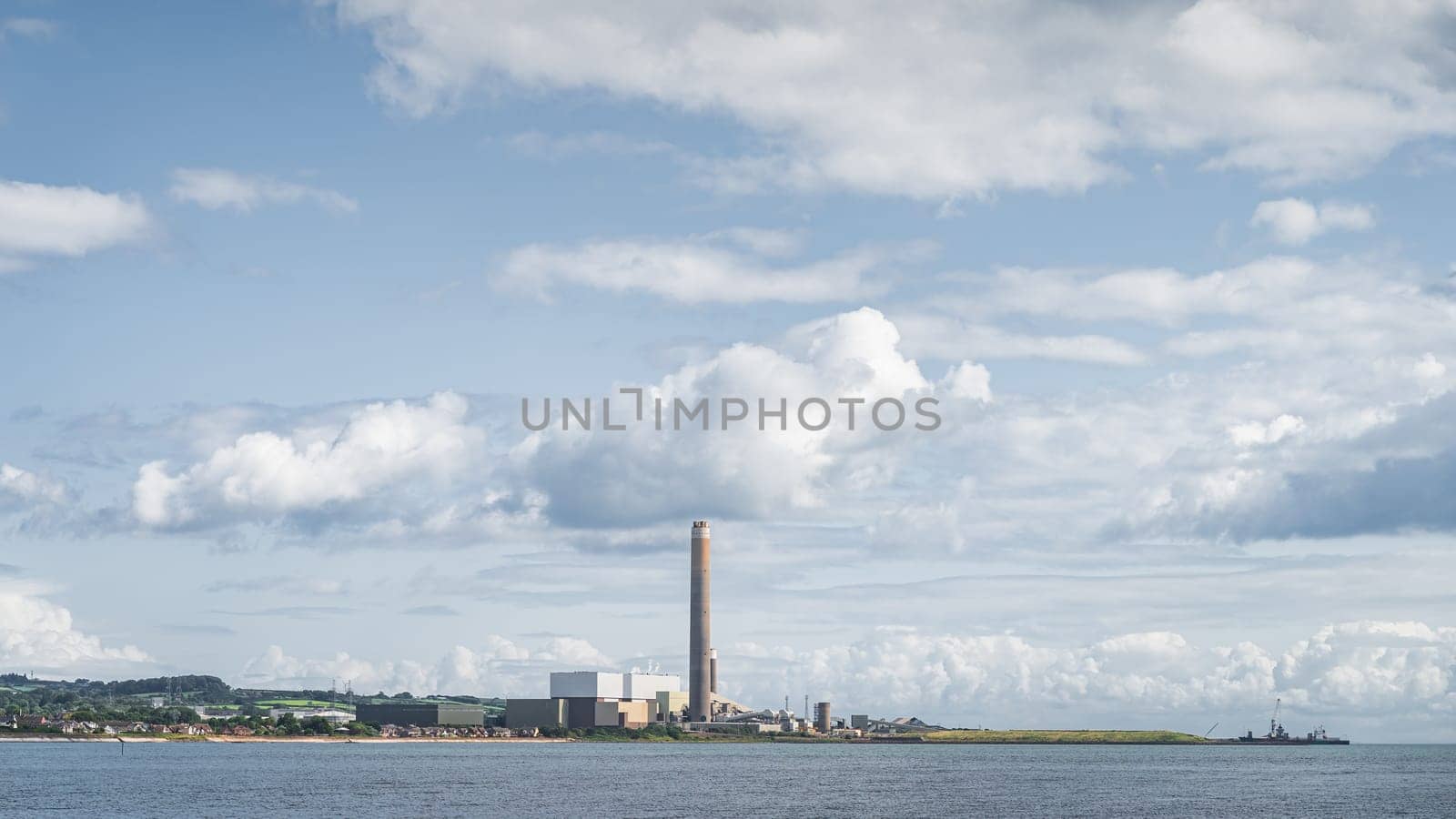 Large factory or plant with tall chimney and industrial harbour on the Northern Ireland coast, Carrickfergus town, County Antrim