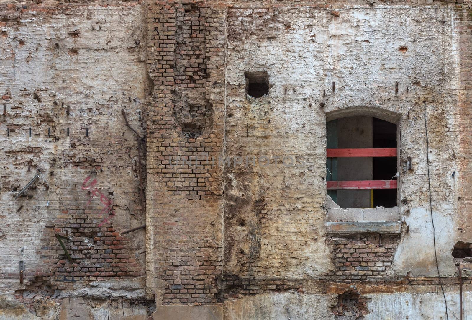 Broken red brick wall and damaged plaster on the background