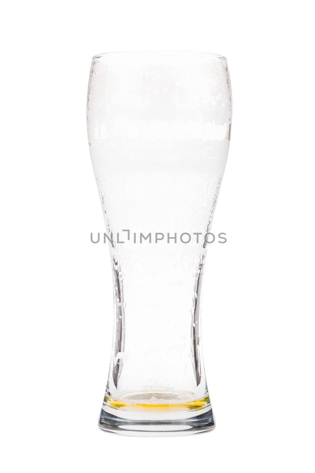Almost empty beer glass. Light lager beer remains in a tall glass. Isolated on white background