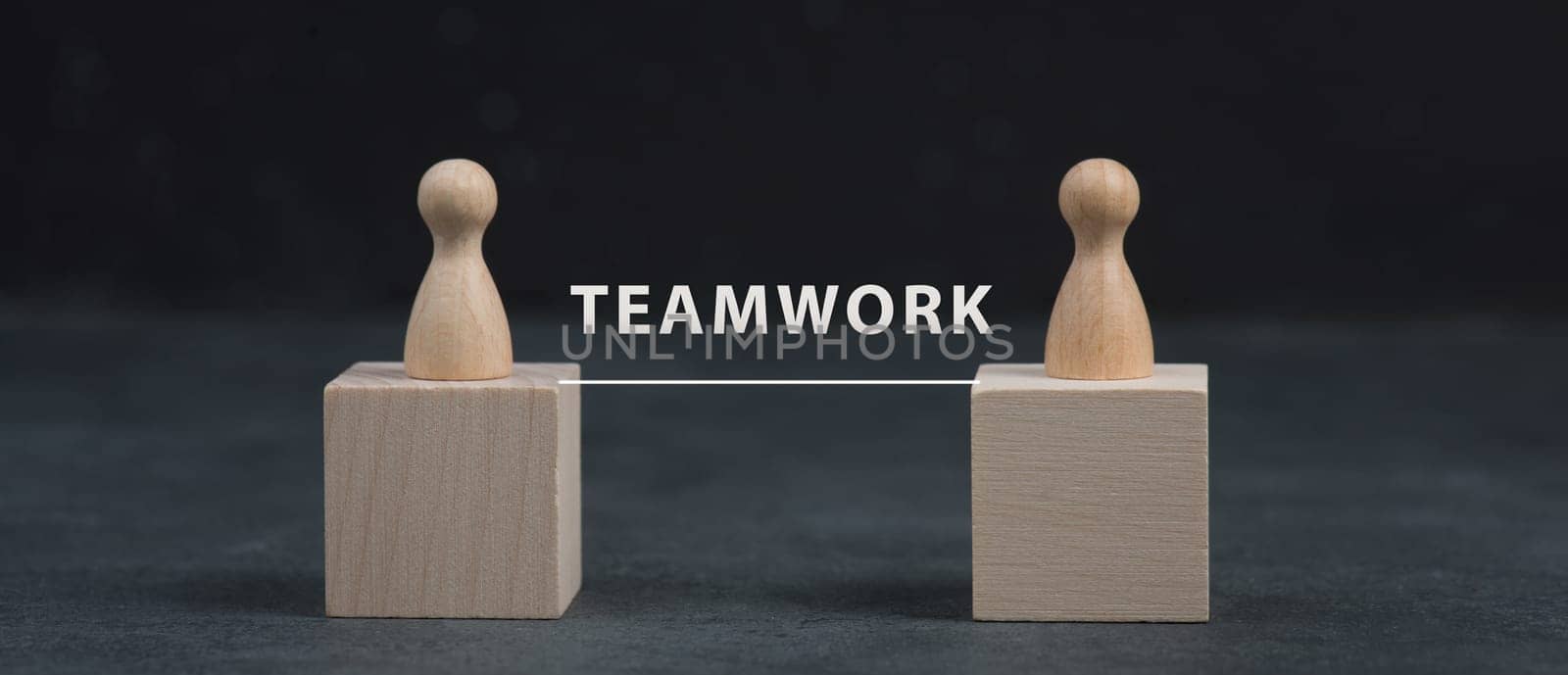Two wooden people connect to build a team, working together