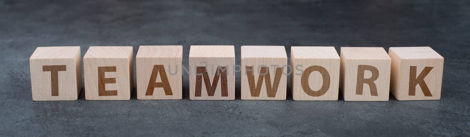 The word teamwork is standing on wooden cubes, dark background