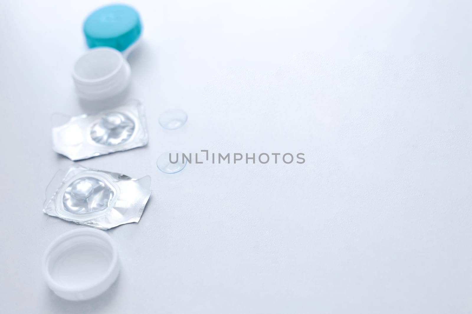 A container for lenses, two sealed lenses and lenses lying on a table on the side on a white background with a place for text. top view, flat lay, copy space, isolate. High quality photo