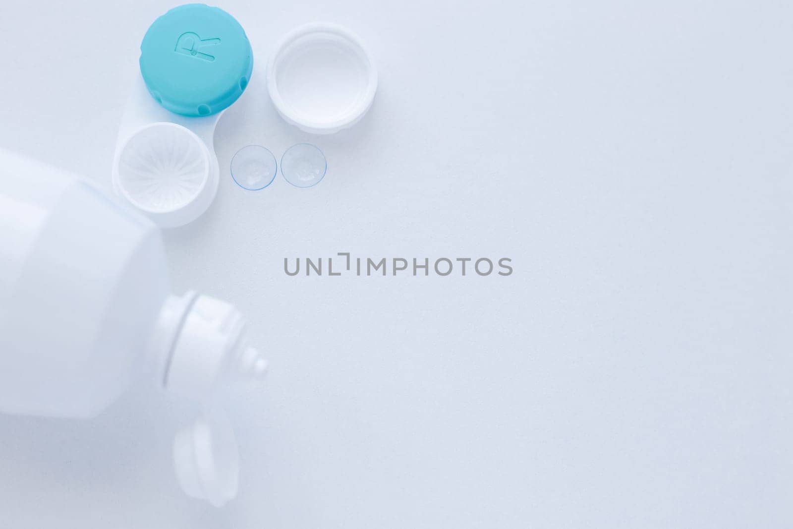 A container for lenses and two contact lenses lie on the side on a white background with space for text. top view, flat lay, copy space, isolate. High quality photo