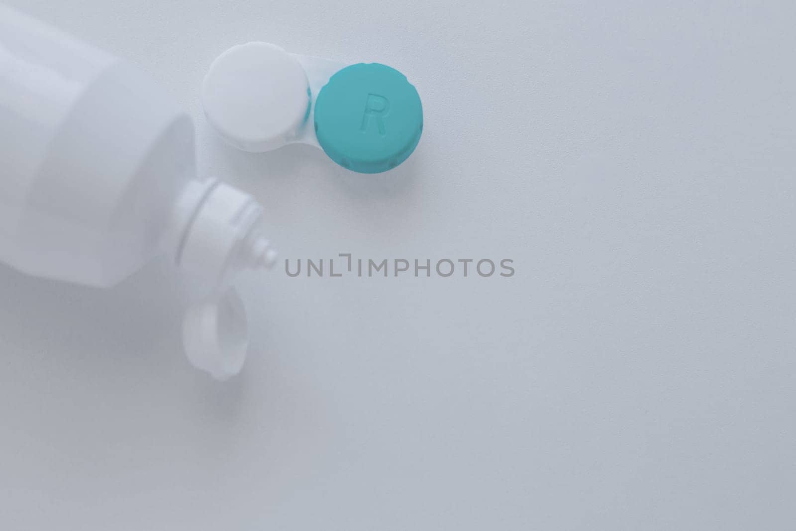 The lens container and the lens storage liquid lie on the side on a white background with space for text. top view, flat lay, copy space, isolate. High quality photo