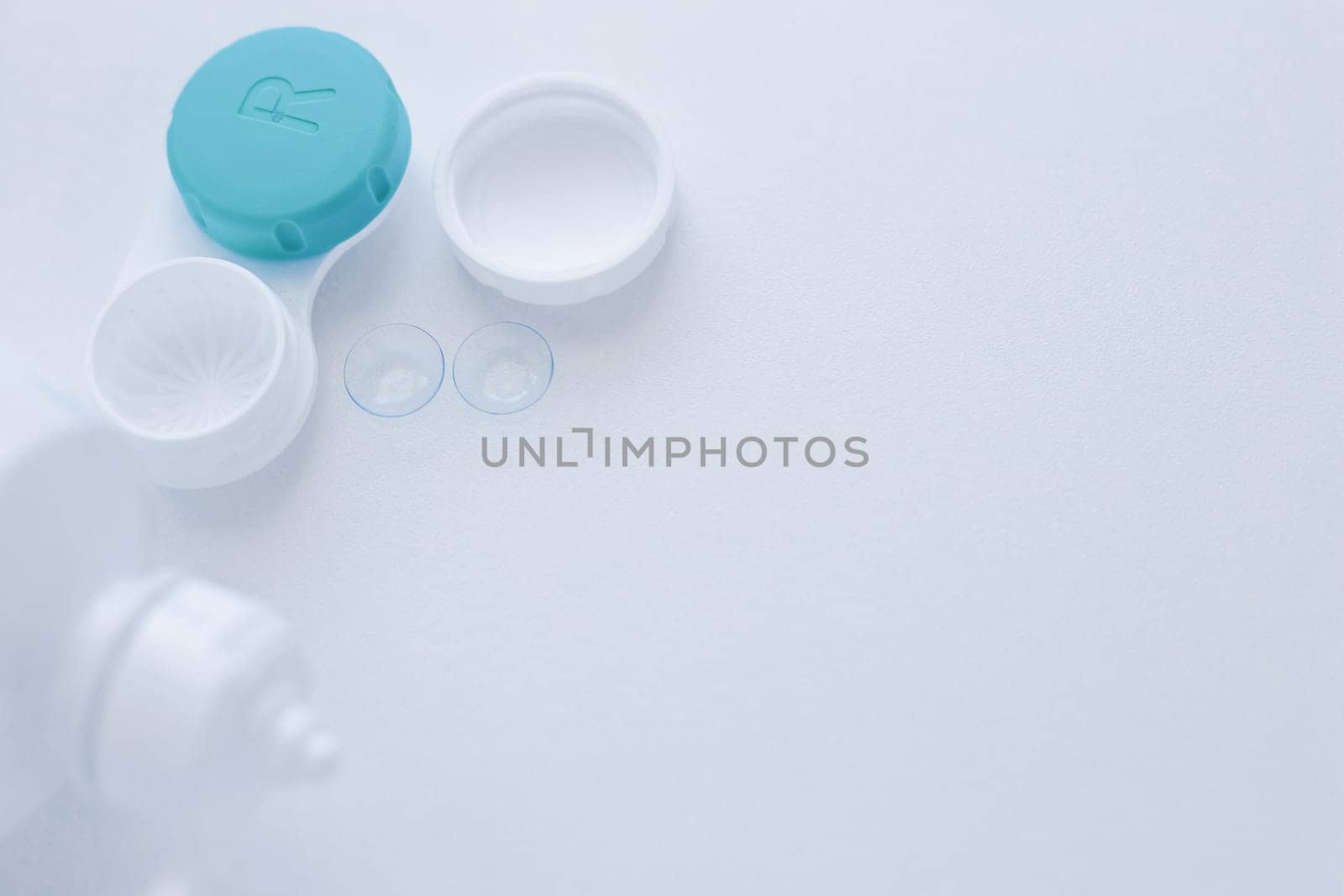 A lens container, a lens storage liquid and two contact lenses lie on the side on a white background with space for text. top view, flat lay, copy space, isolate. High quality photo