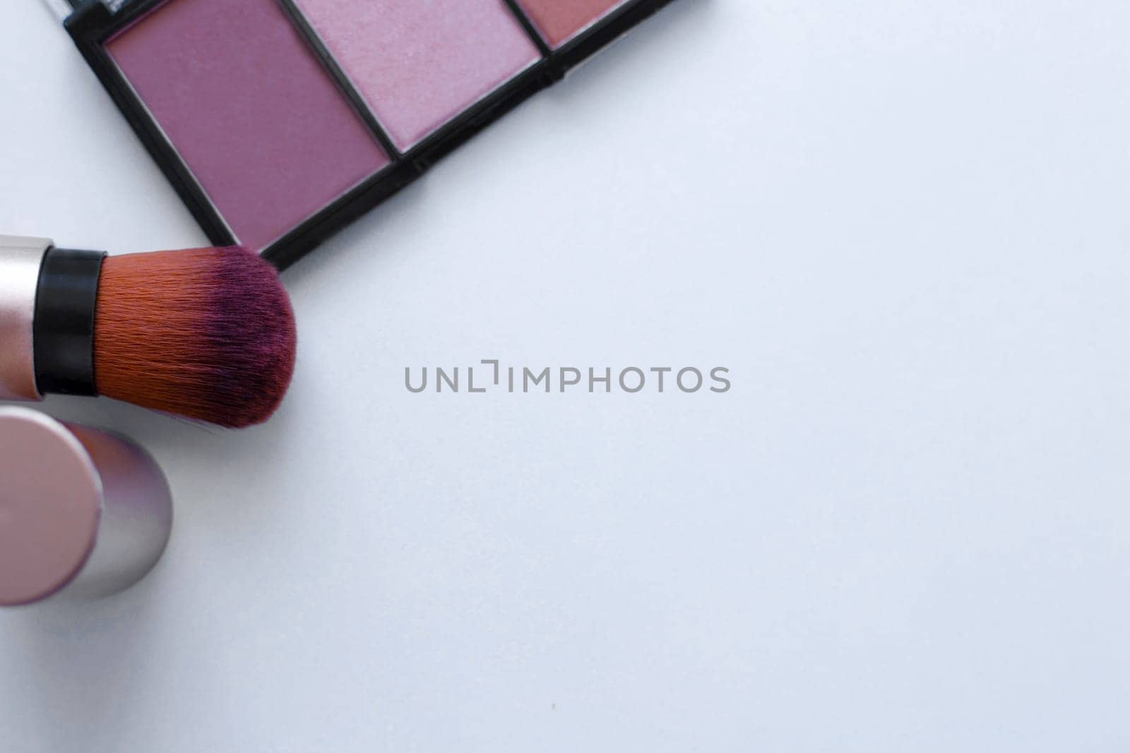A chocolate-colored bronzer and a highlighter and a brush for applying blush on a white background with a place for text. top view, flat lay, copy space, isolate. High quality photo