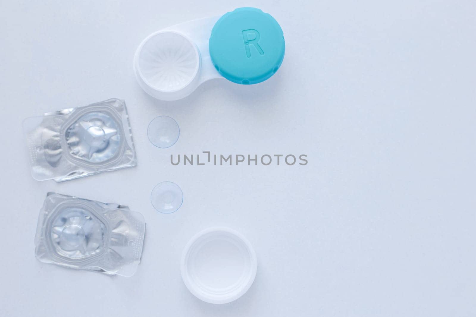 A container for lenses, two sealed lenses and lenses lying on a table on the side on a white background with a place for text. top view, flat lay, copy space, isolate. High quality photo