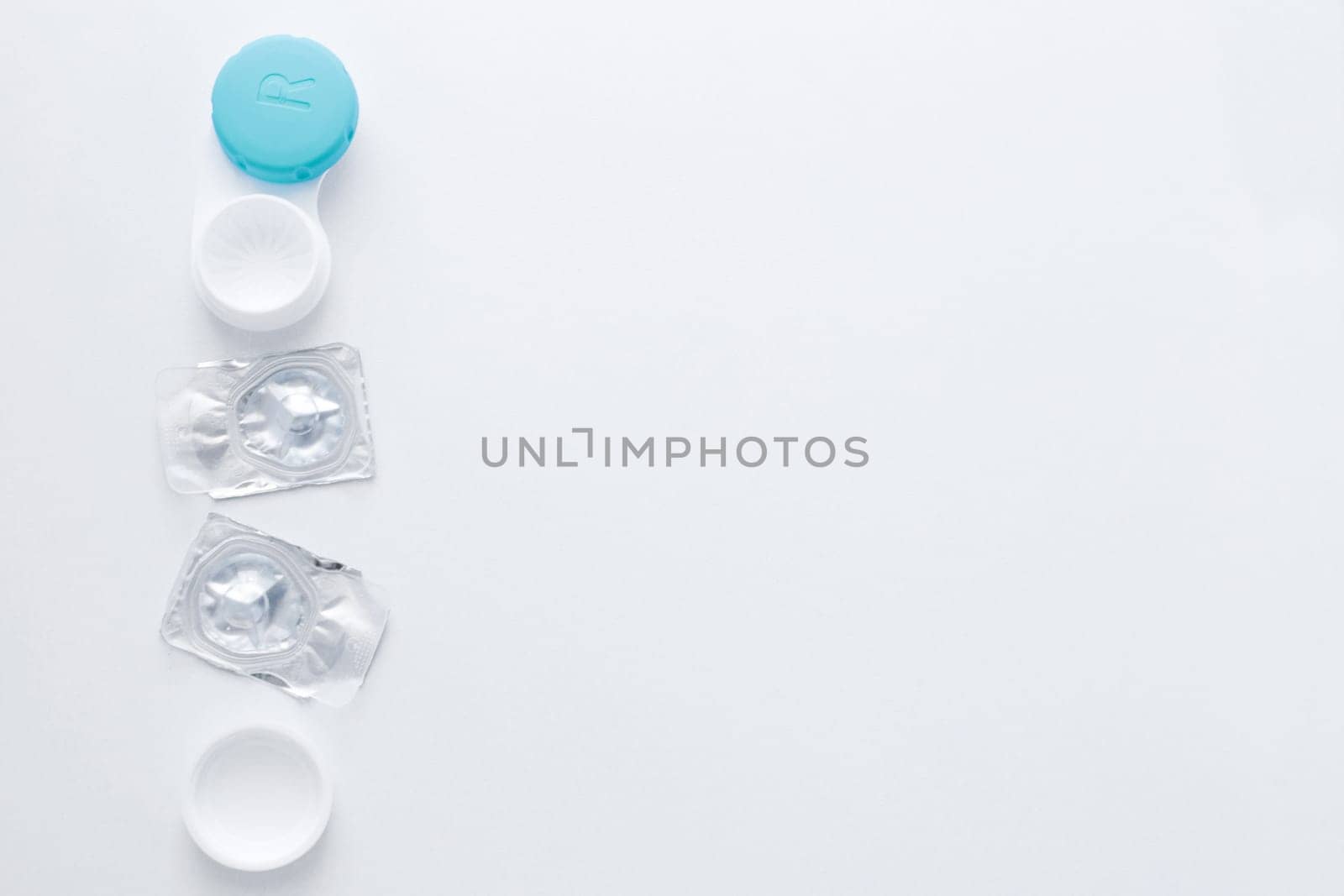 A container for lenses and two sealed lenses lie on the side on a white background with space for text.top view, flat lay, copy space, isolate. High quality photo