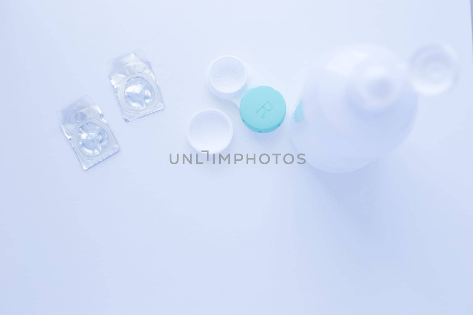A lens remover, a lens storage container and two contact lenses lie on top of the photo on a white background. top view, flat lay, copy space, isolate. High quality photo