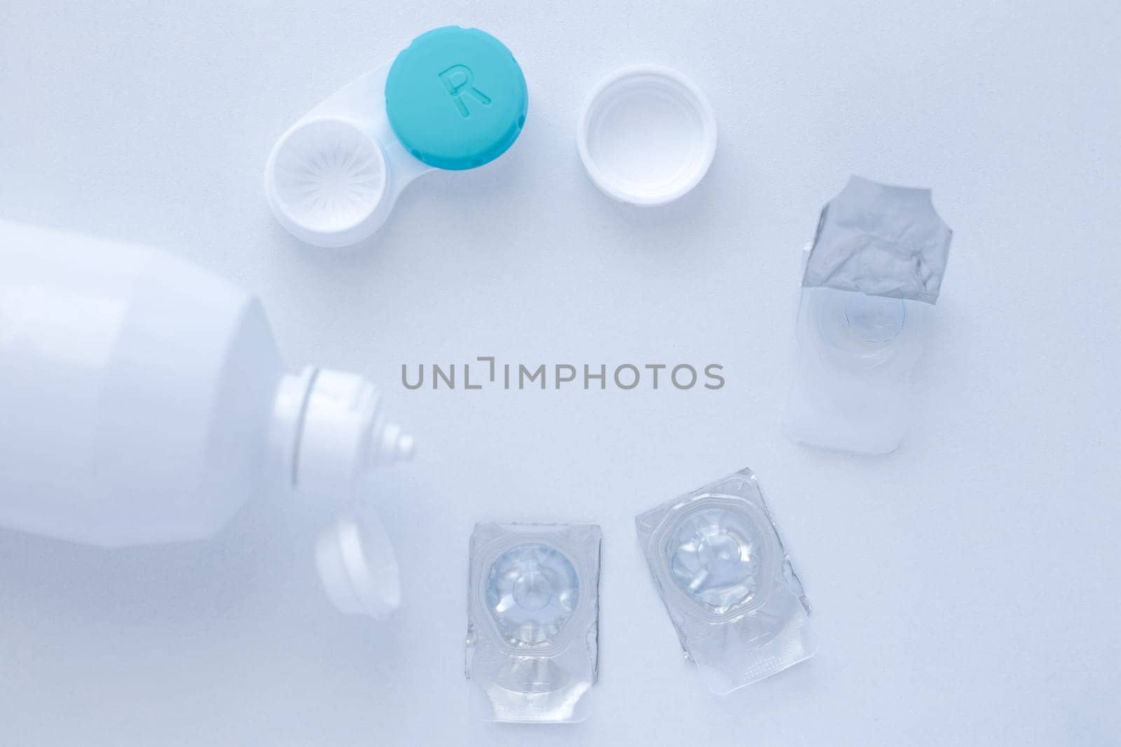 Lens remover, a container for storing lenses and two contact lenses lie on the sides on a white background, there is a place for text. top view, flat lay, copy space, isolate. High quality photo