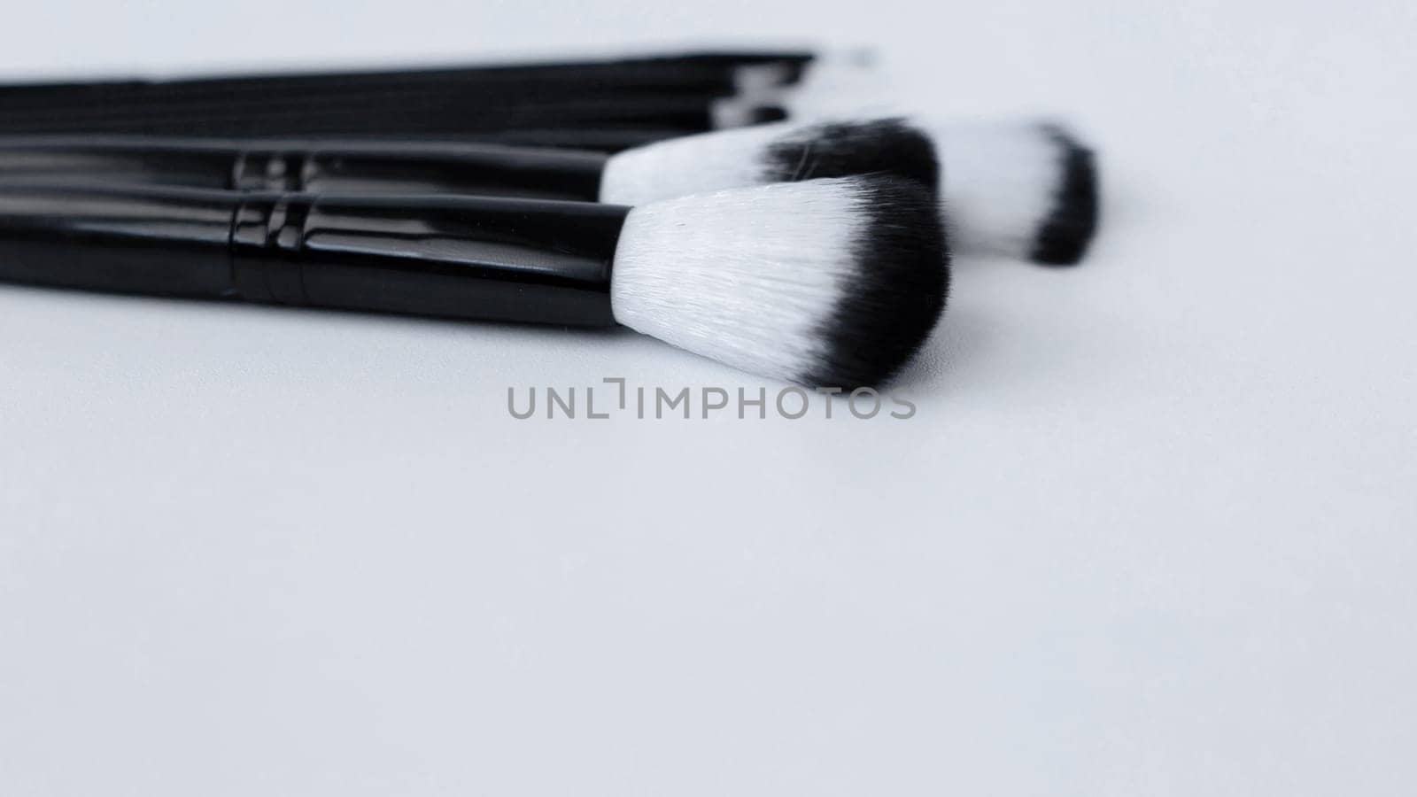 Black brushes with white and black pile for makeup of different sizes lie on a white background on top.top view, flat lay, copy space, isolate. High quality photo