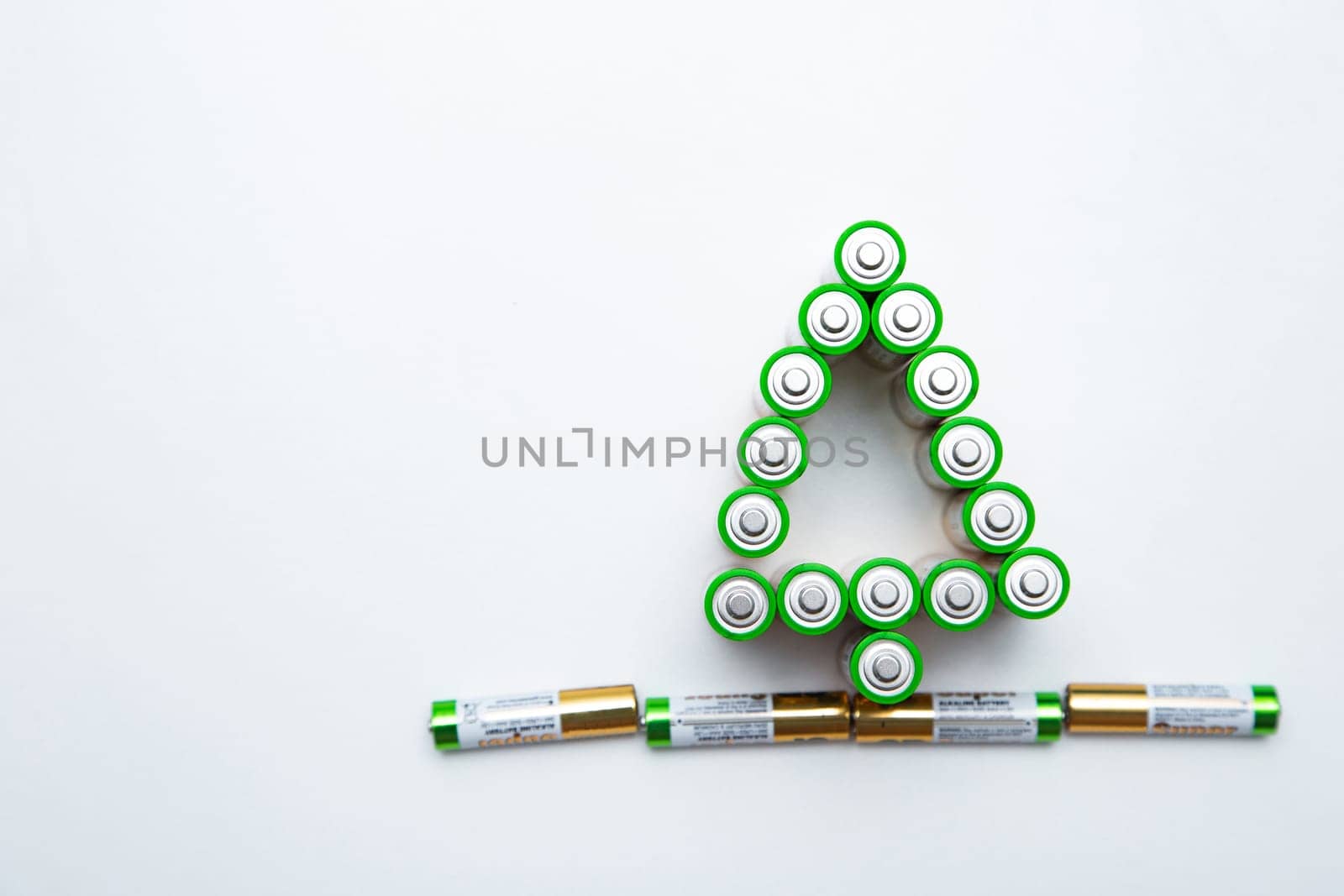 The batteries are in the shape of a Christmas tree on a white background. top view, flat lay, copy space, isolate. High quality photo