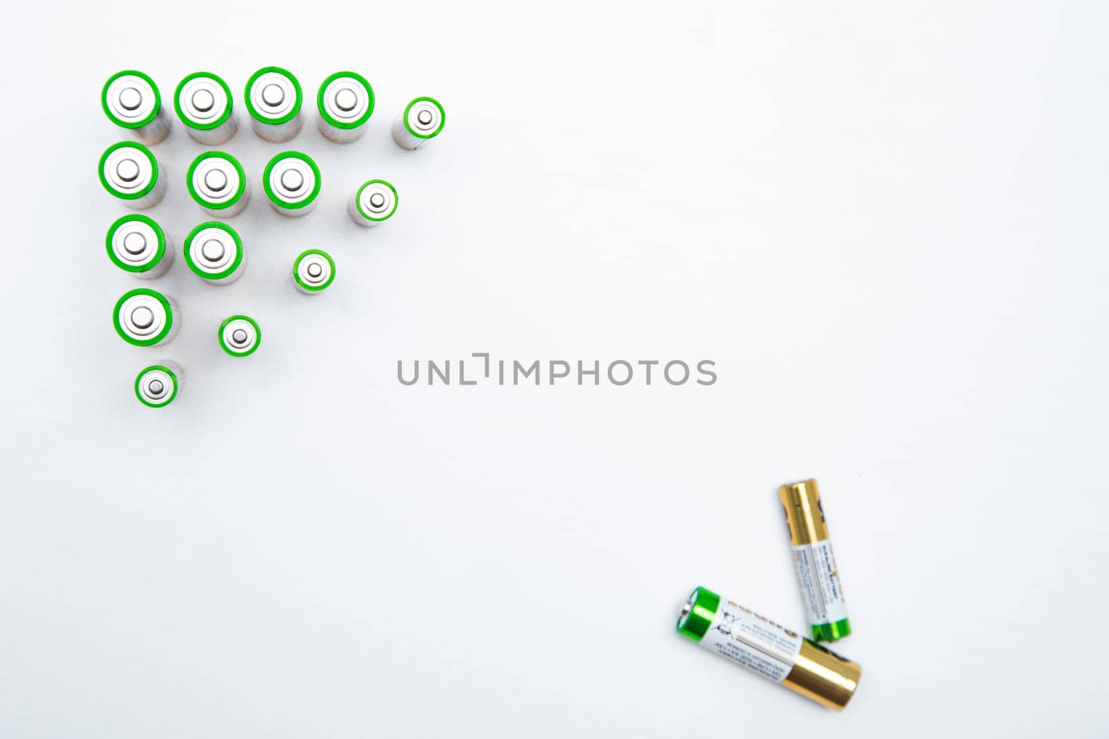 The batteries are placed in a triangle in the upper corner of the photo, in the opposite lower corner there are two batteries on a white background. top view, flat lay, copy space, isolate. High quality photo