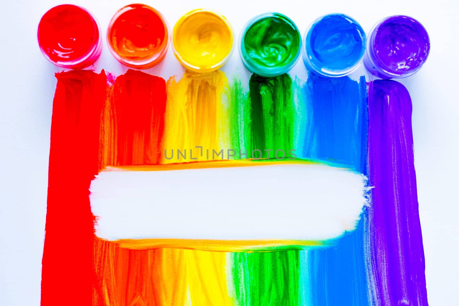 Colorful lines drawn vertically with paint in the form of a rainbow with a white place for text in the middle on a white background. top view, flat lay, copy space, isolate. High quality photo