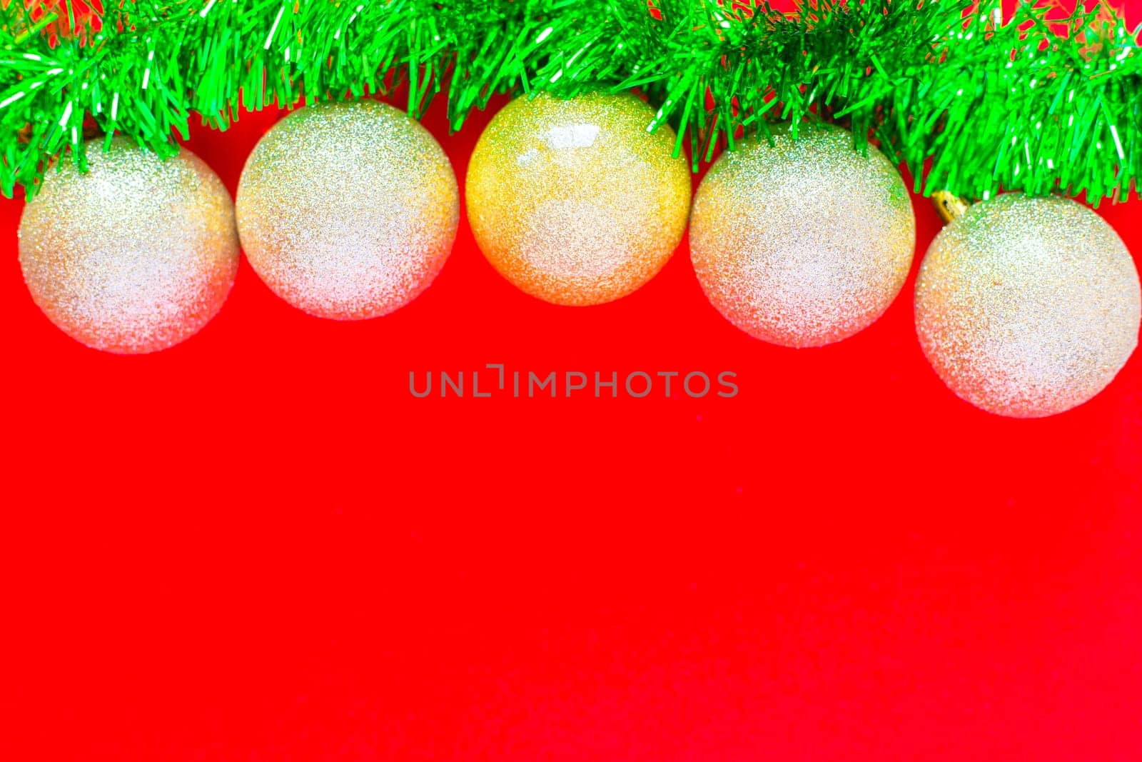 Christmas balls of silver color hang on a green fluffy garland tinsel of green color on top of the photo on a red background. top view, flat lay, copy space, isolate. High quality photo