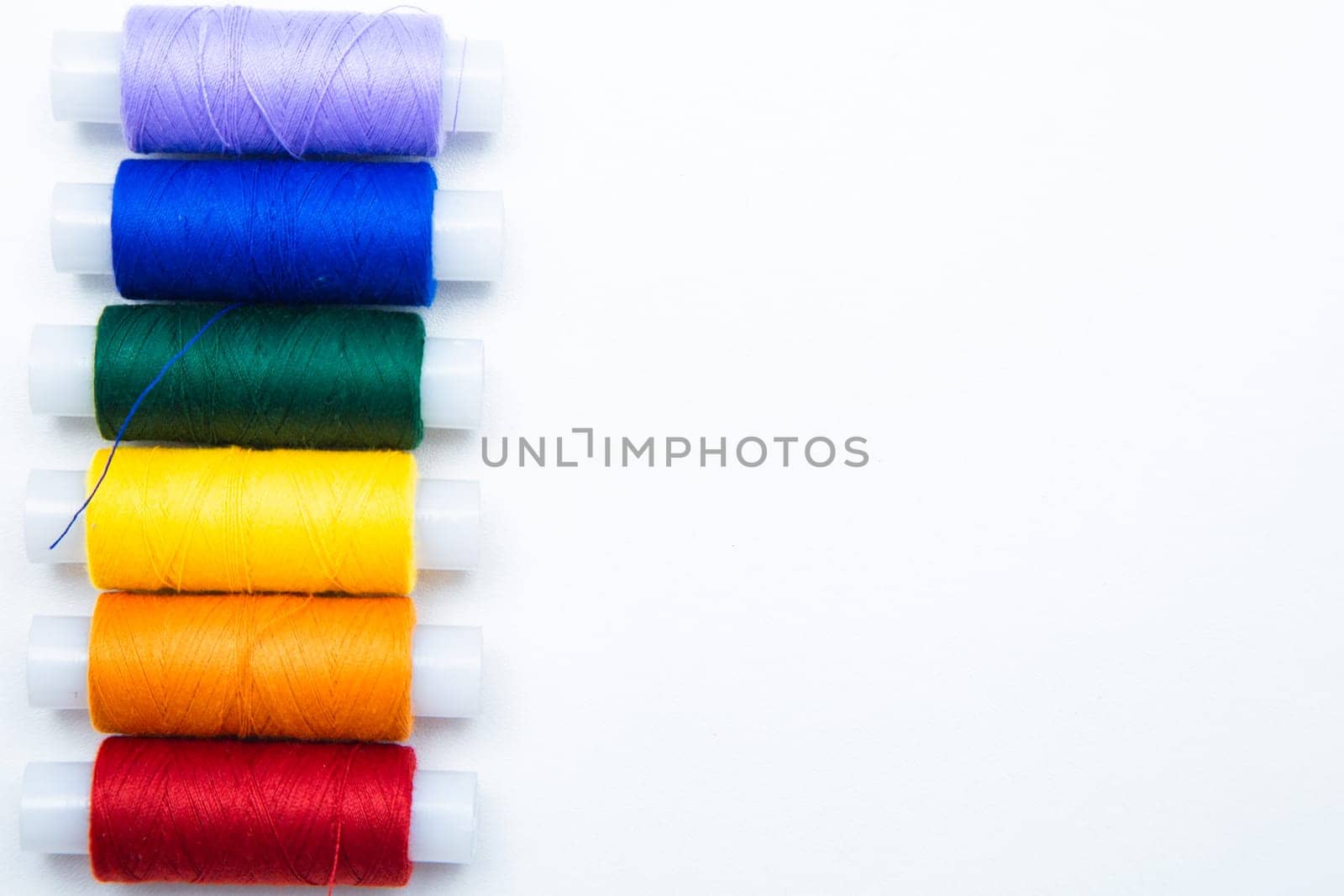 Skeins with threads are lined up in a row according to the color of the rainbow. top view, flat lay, copy space, isolate High quality photo