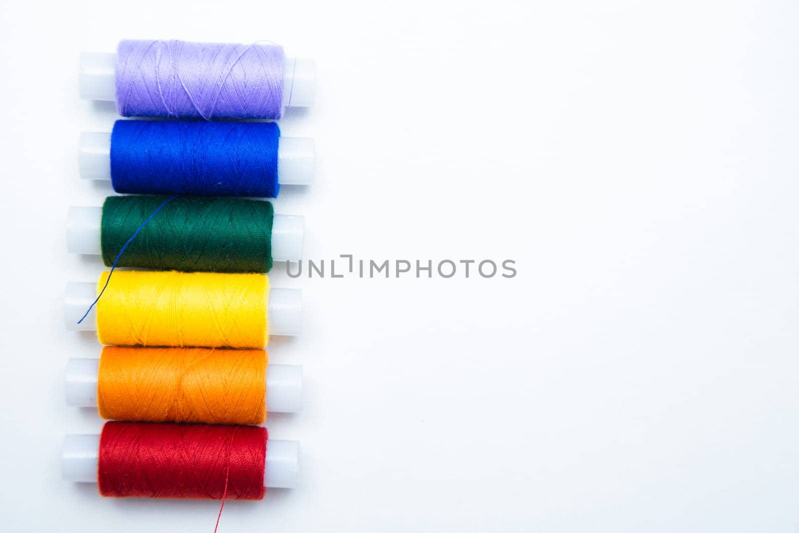 Skeins with threads are lined up in a row according to the color of the rainbow. top view, flat lay, copy space, isolate High quality photo