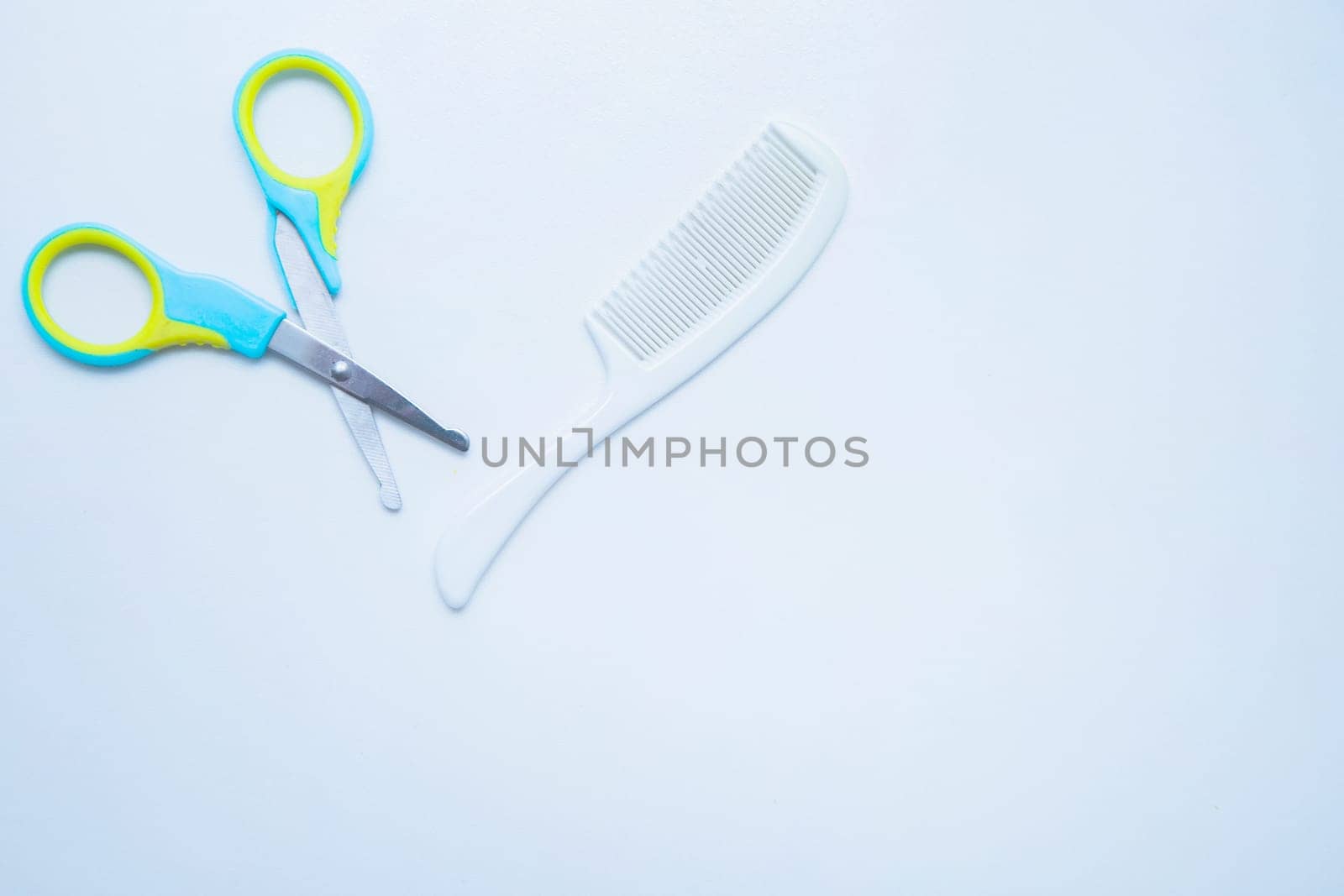 Children's scissors for cutting nails and a children's comb are on a white background. top view, flat lay, copy space, isolate. High quality photo