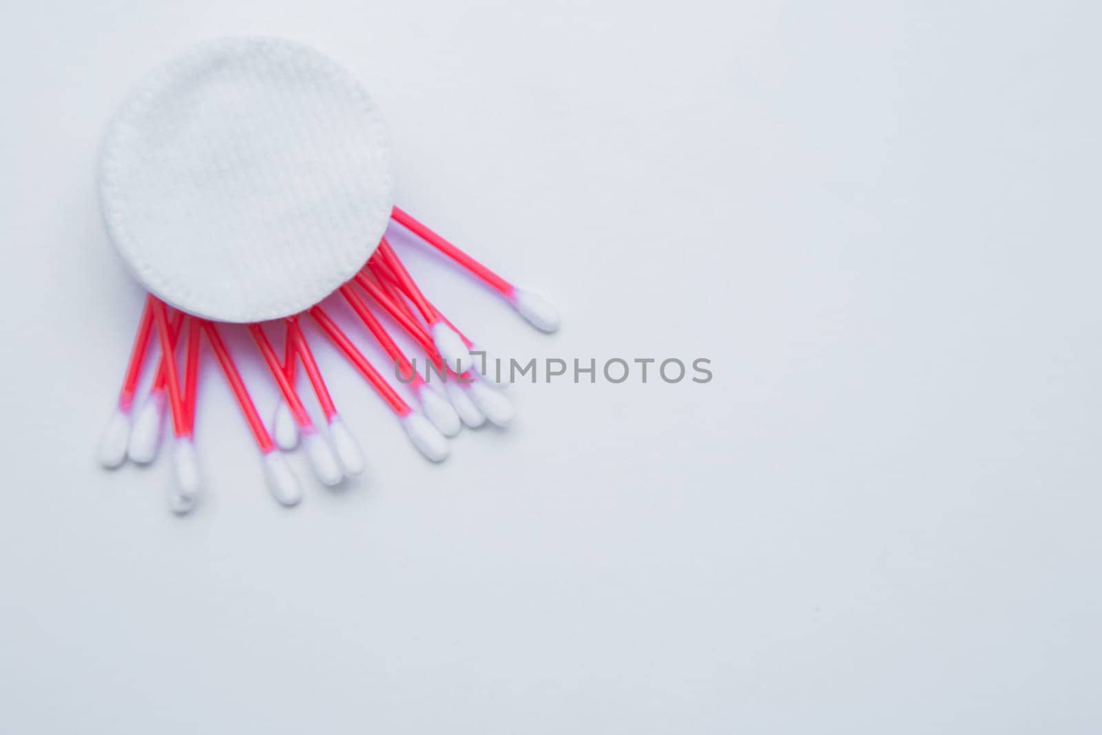 Disposable ear sticks with a red wand and white disposable cotton sponges lie on a white background.. top view, flat lay, copy space, isolate. High quality photo