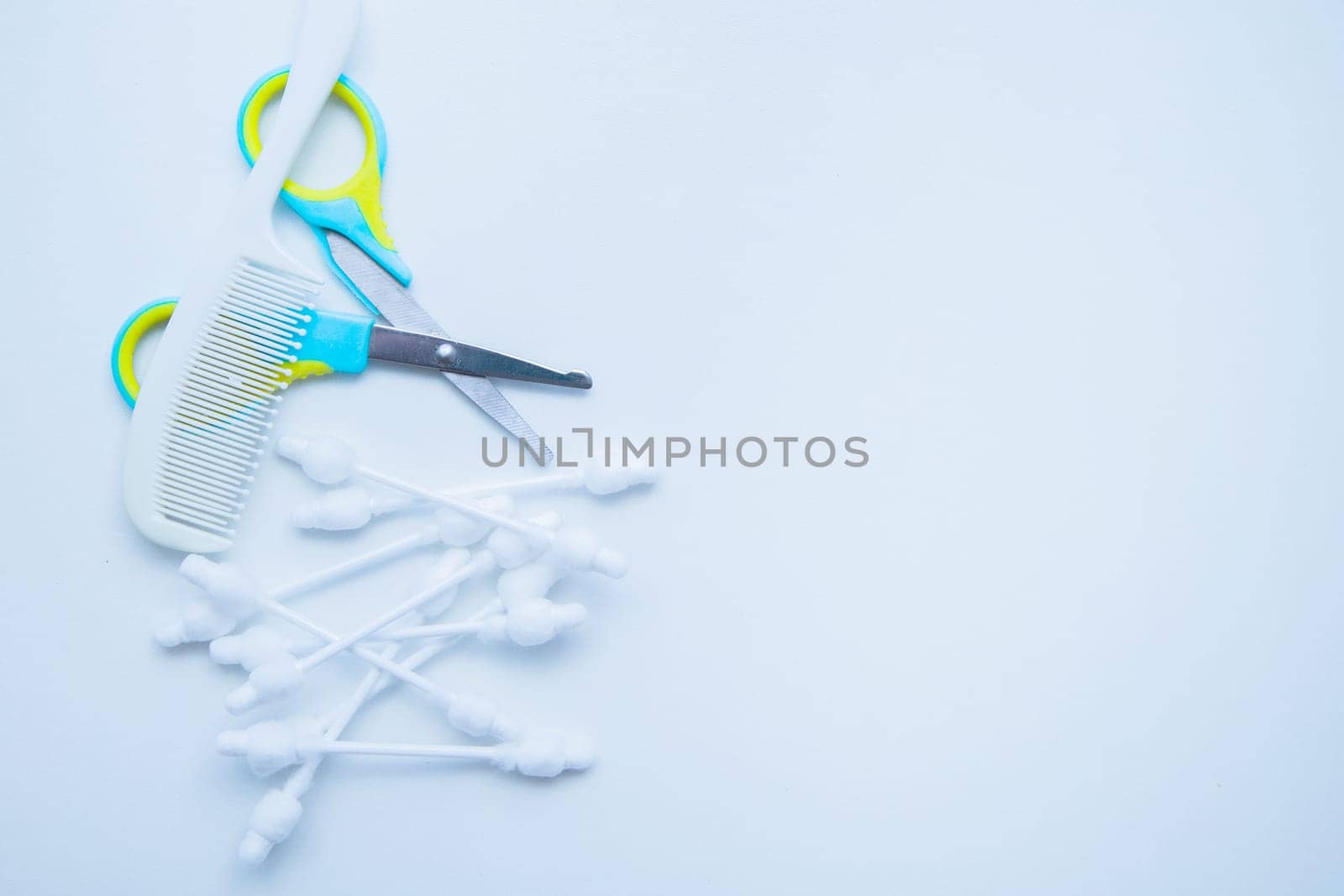 Children's scissors for cutting nails, children's ear sticks and a children's comb are on a white background. High quality photo