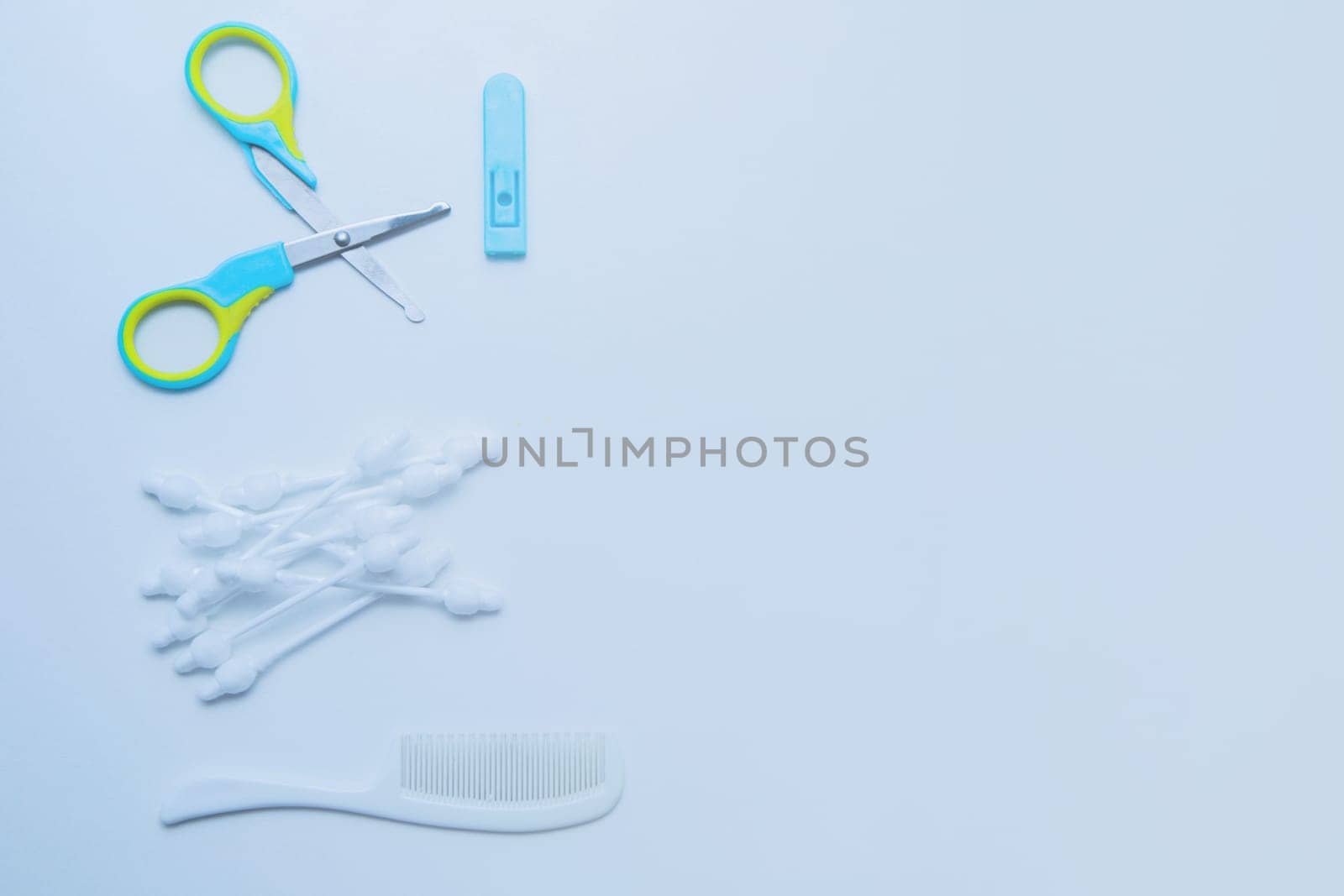 Children's scissors for cutting nails, children's ear sticks and a children's comb are on a white background. High quality photo
