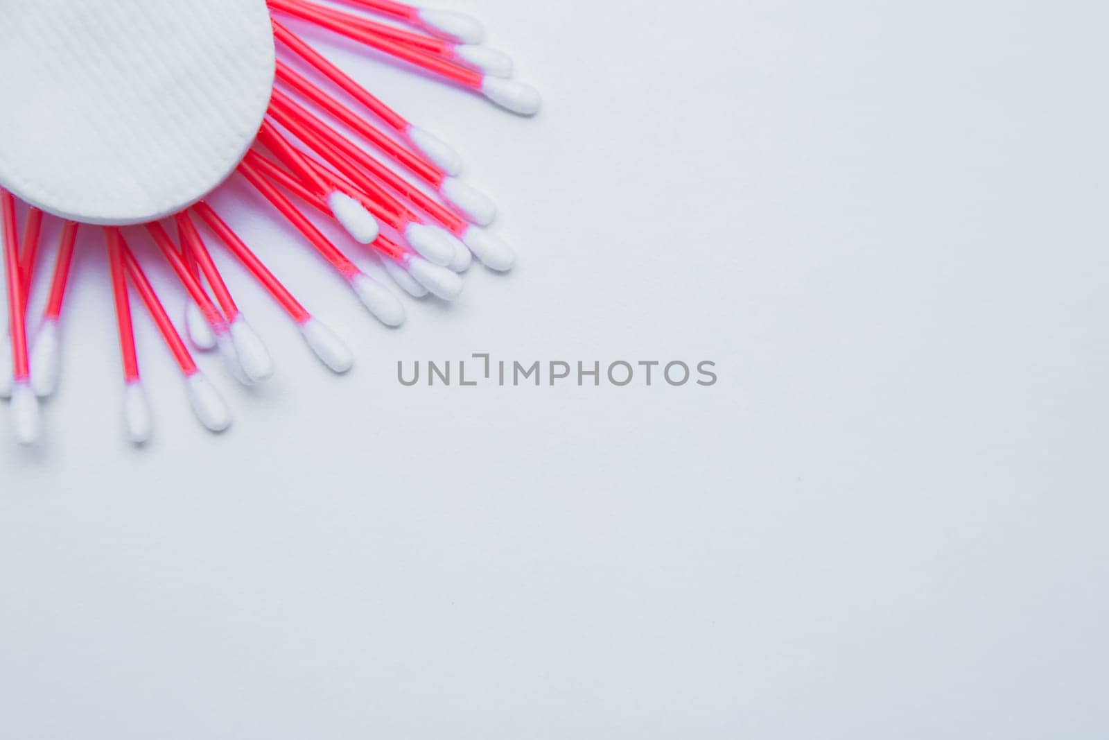 Disposable ear sticks with a red wand and white disposable cotton sponges lie on a white background.. top view, flat lay, copy space, isolate. High quality photo