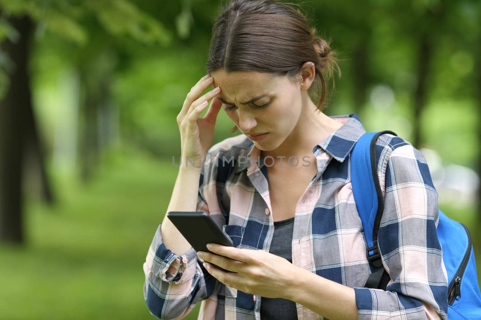 Concerned student checking smart phone in a park