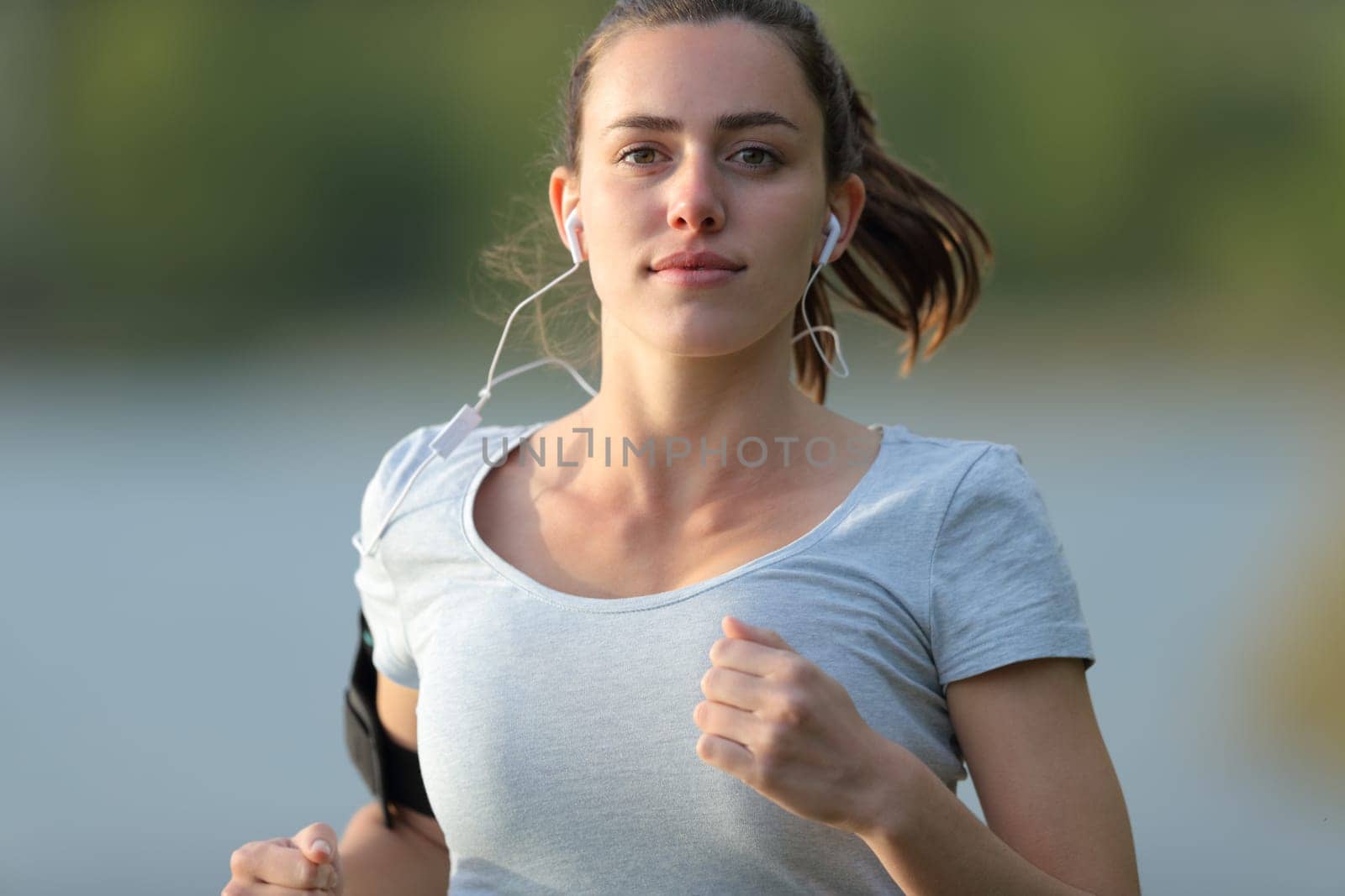 Front view portrait of a runner running with earbuds in a lake