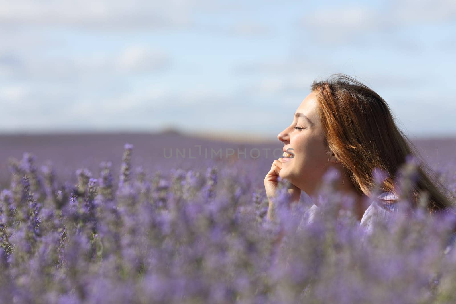 Side view portrait of a happy woman relaxing in the middle of lavender field