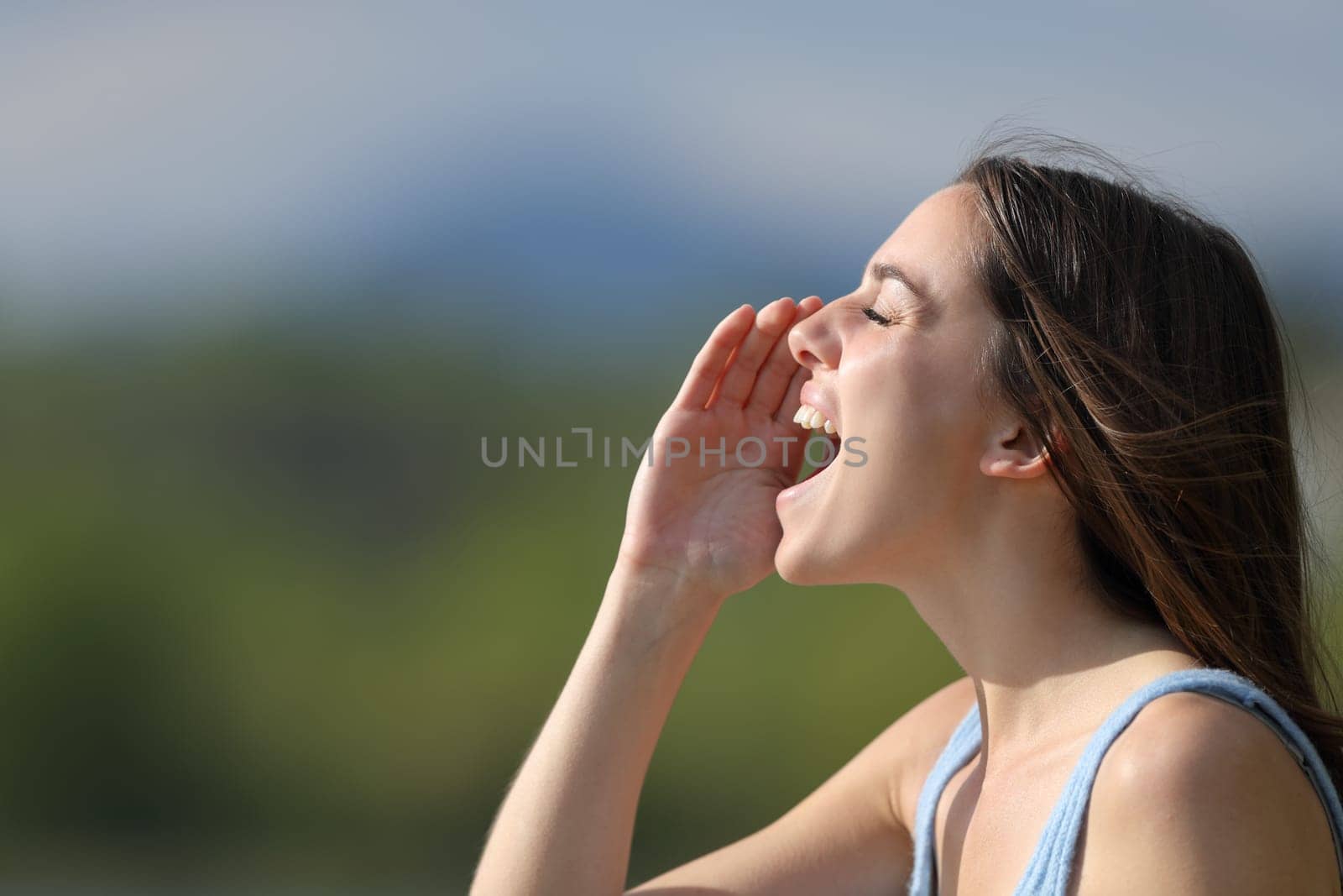 Profile of a woman shouting loudly in nature