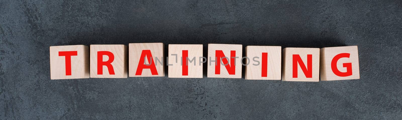 The word training is standing in red letters on wooden cubes, dark background