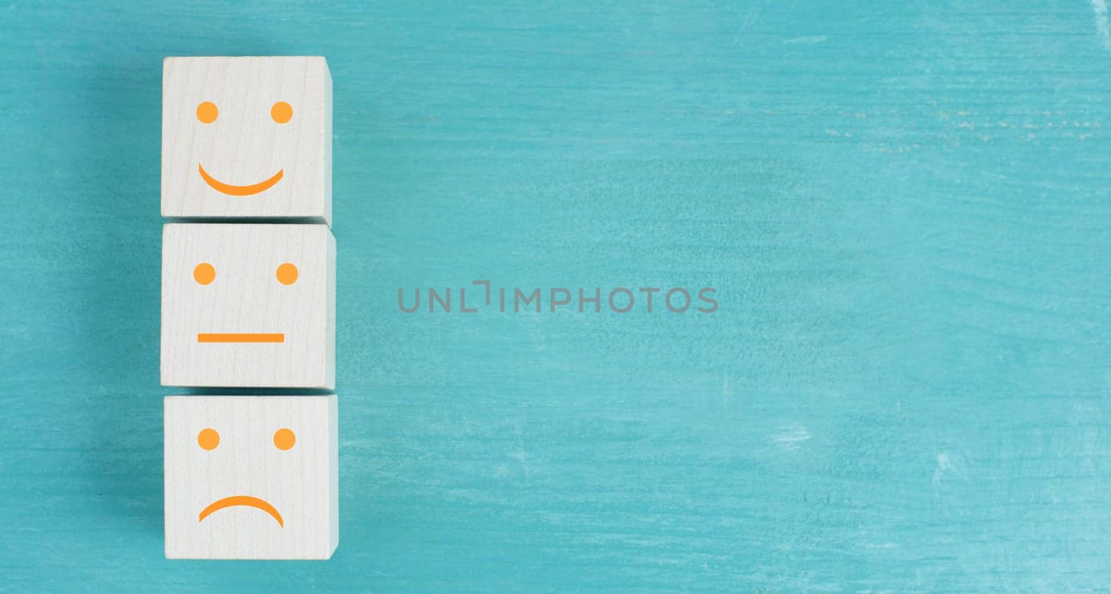 Three wooden cubes with smiling and sad faces on a blue bakcground, customer rating