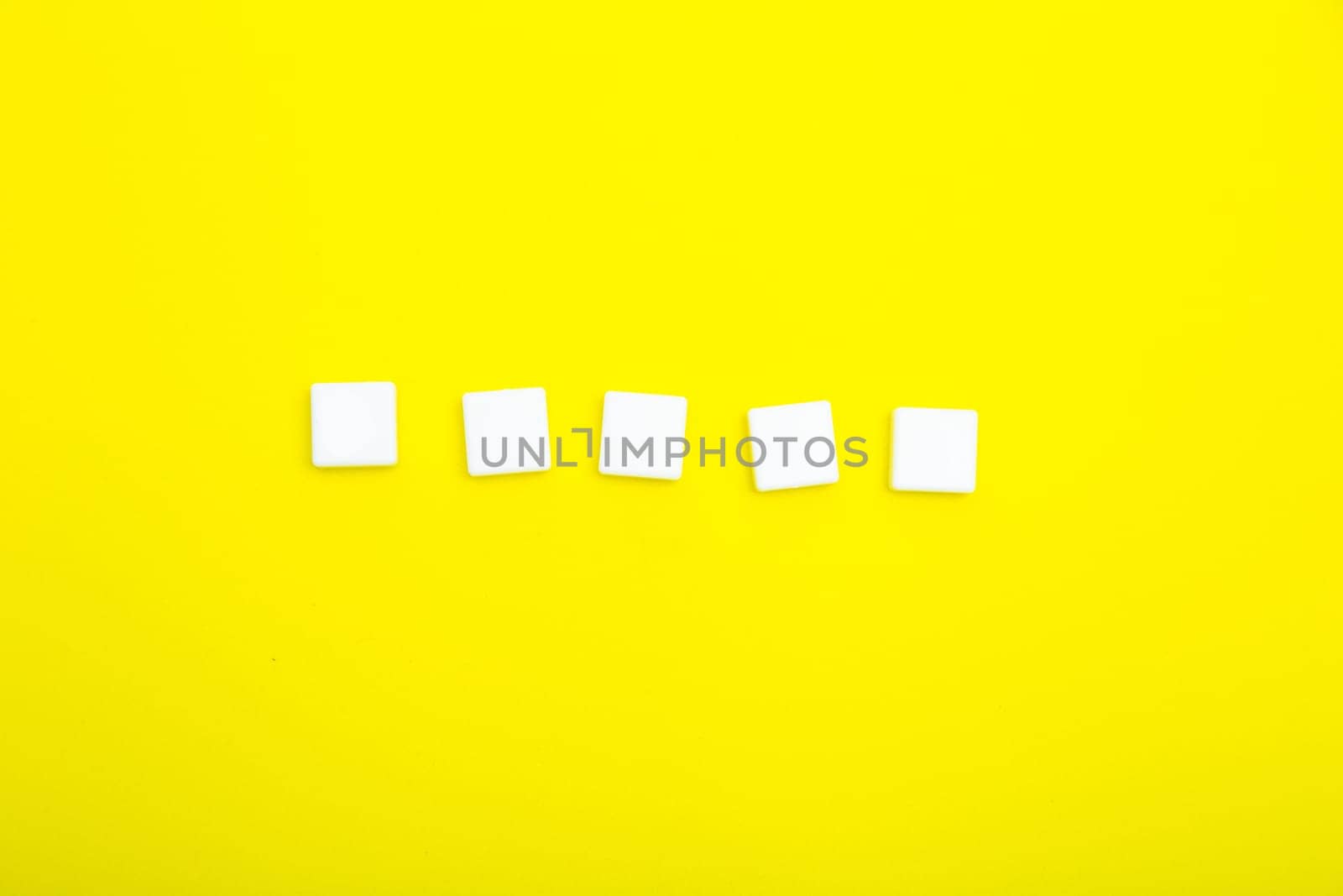 Five white empty squares for letters on a yellow background. High quality photo