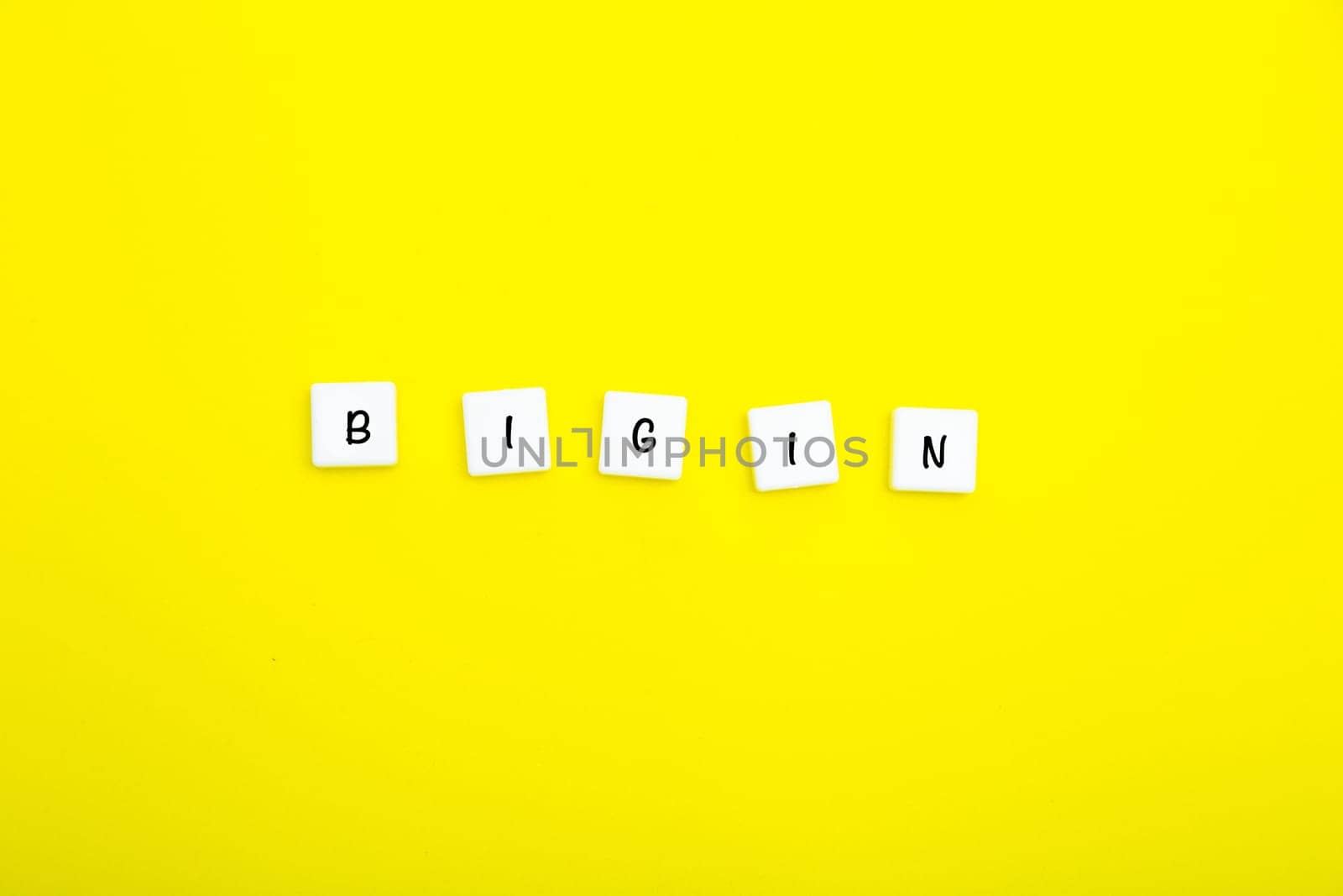 The word BEGIN is written in letters on small white squares on a yellow background. High quality photo