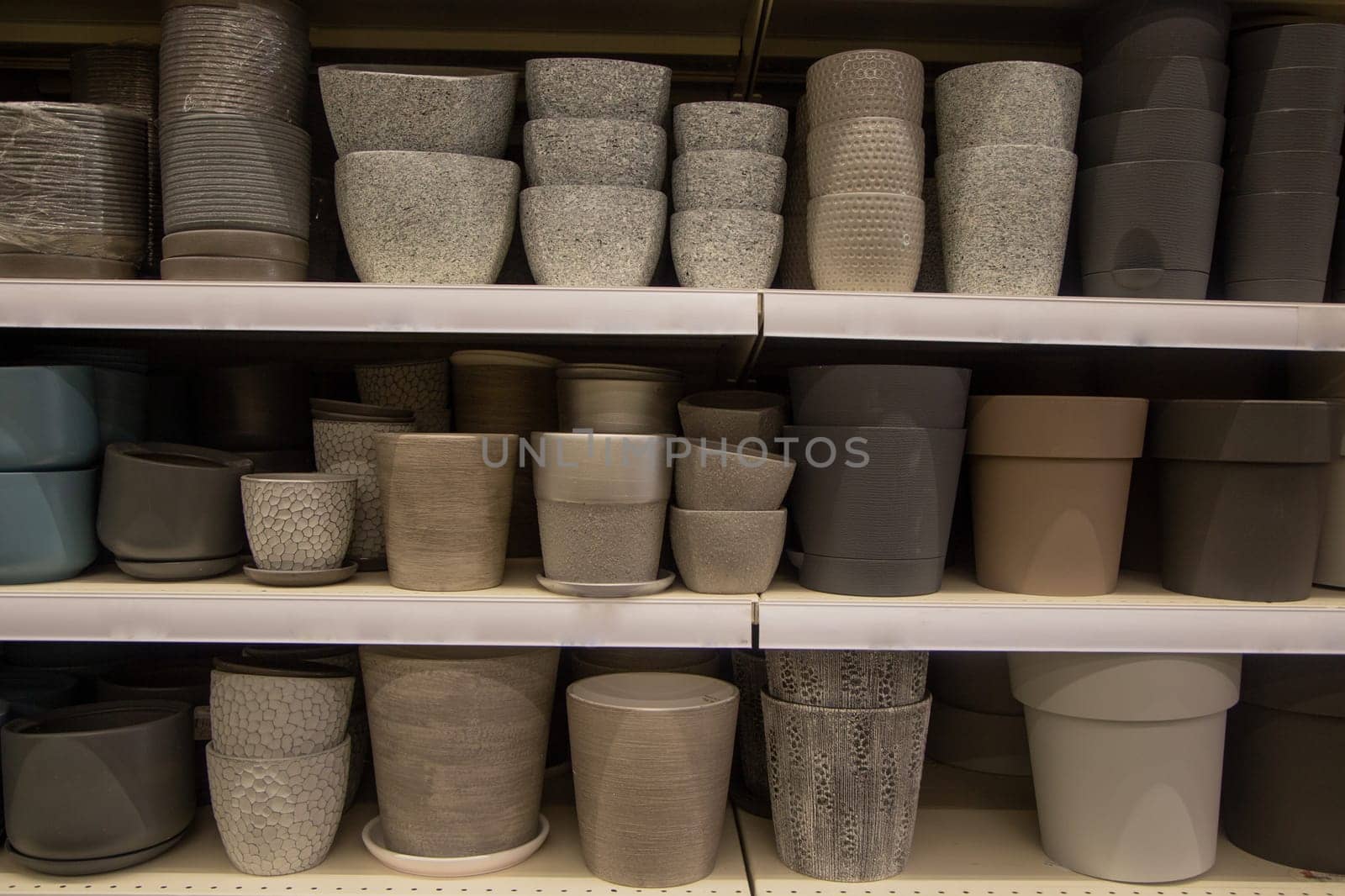 Pots for flowers of light and dark shades are on three shelves. High quality photo