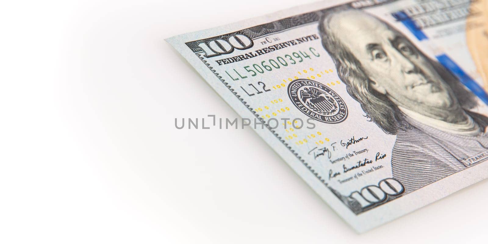 A hundred-dollar bill on a white background. The one hundred North American dollars bill is not fully positioned diagonally. Selective focus on a portion of the 100 bill. Color style. Place for logo, lettering, layout, layout.