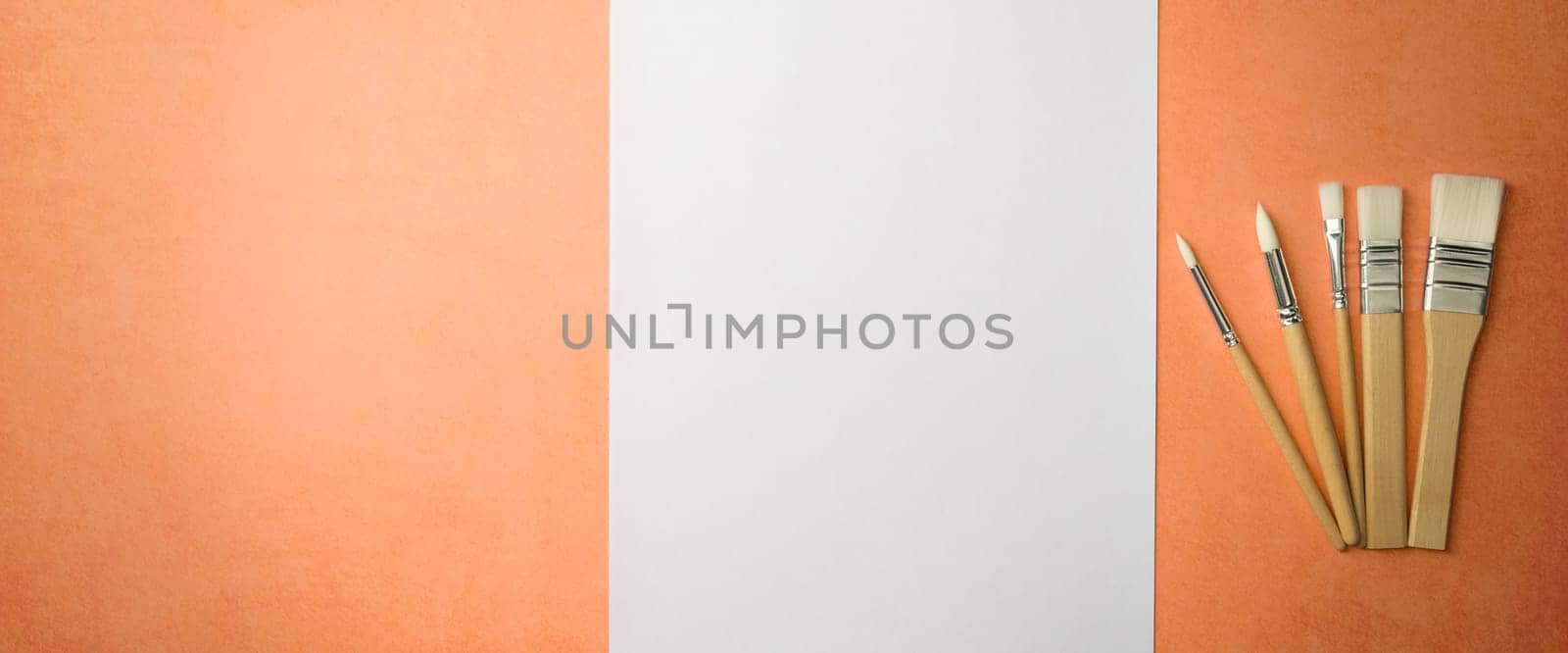 A clean white sheet and brushes on a textured background with space to copy. Layout, mockup space for text and drawing.