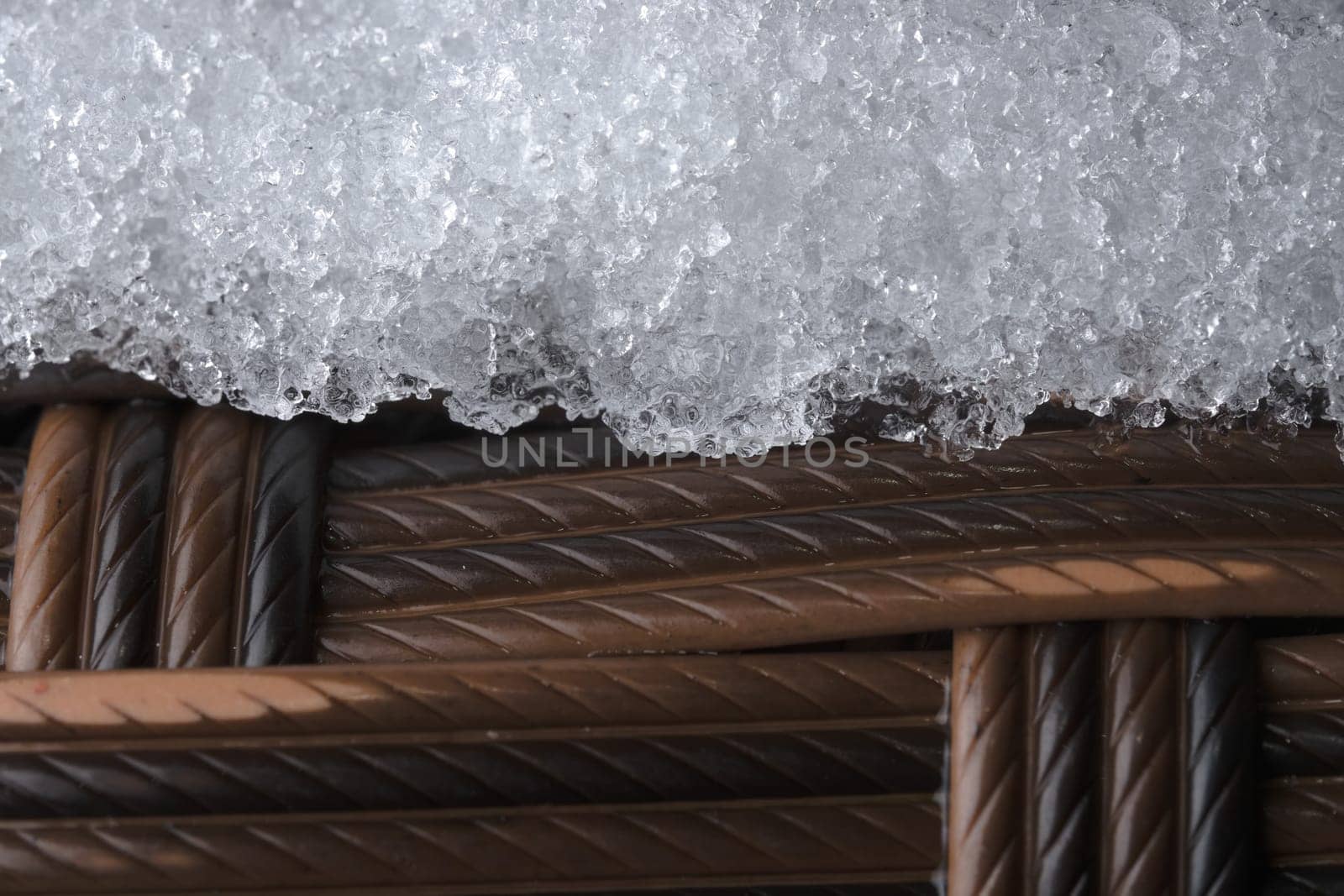 Thick frost or snow on textured plastic garden furniture. Full frame abstract image, from a super close up macro perspective. Cold winter weather